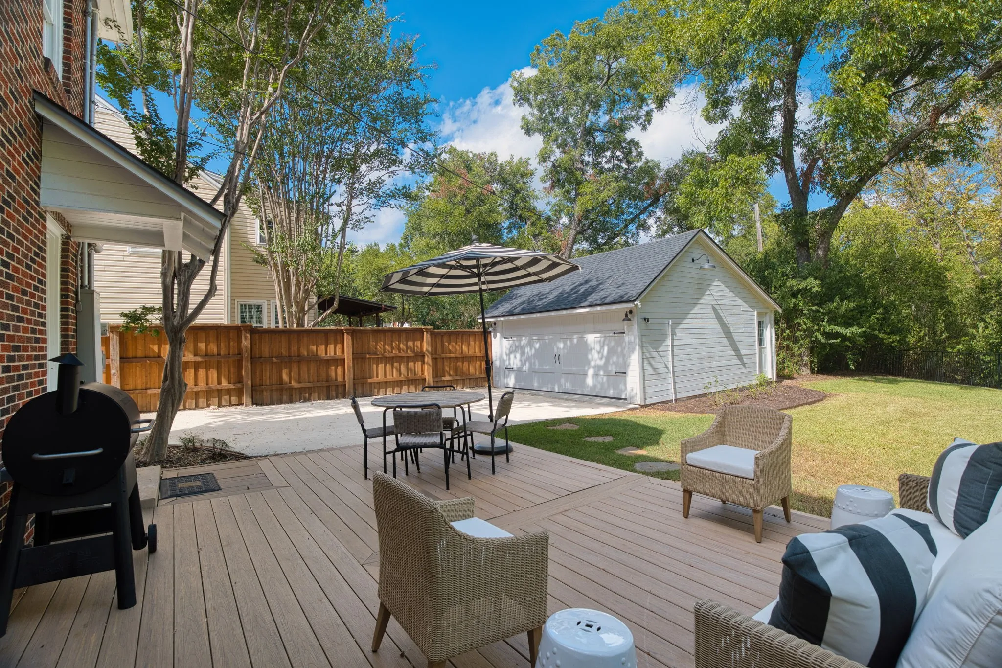 Expansive outdoor deck with a detached garage, lush lawn, and privacy fencing