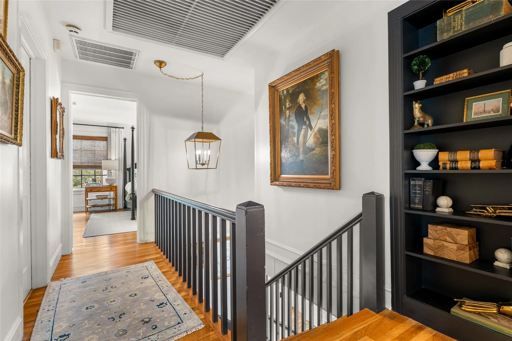 Hardwood flooring, painted banister, built-in shelving, recessed lighting, and a hanging light fixture