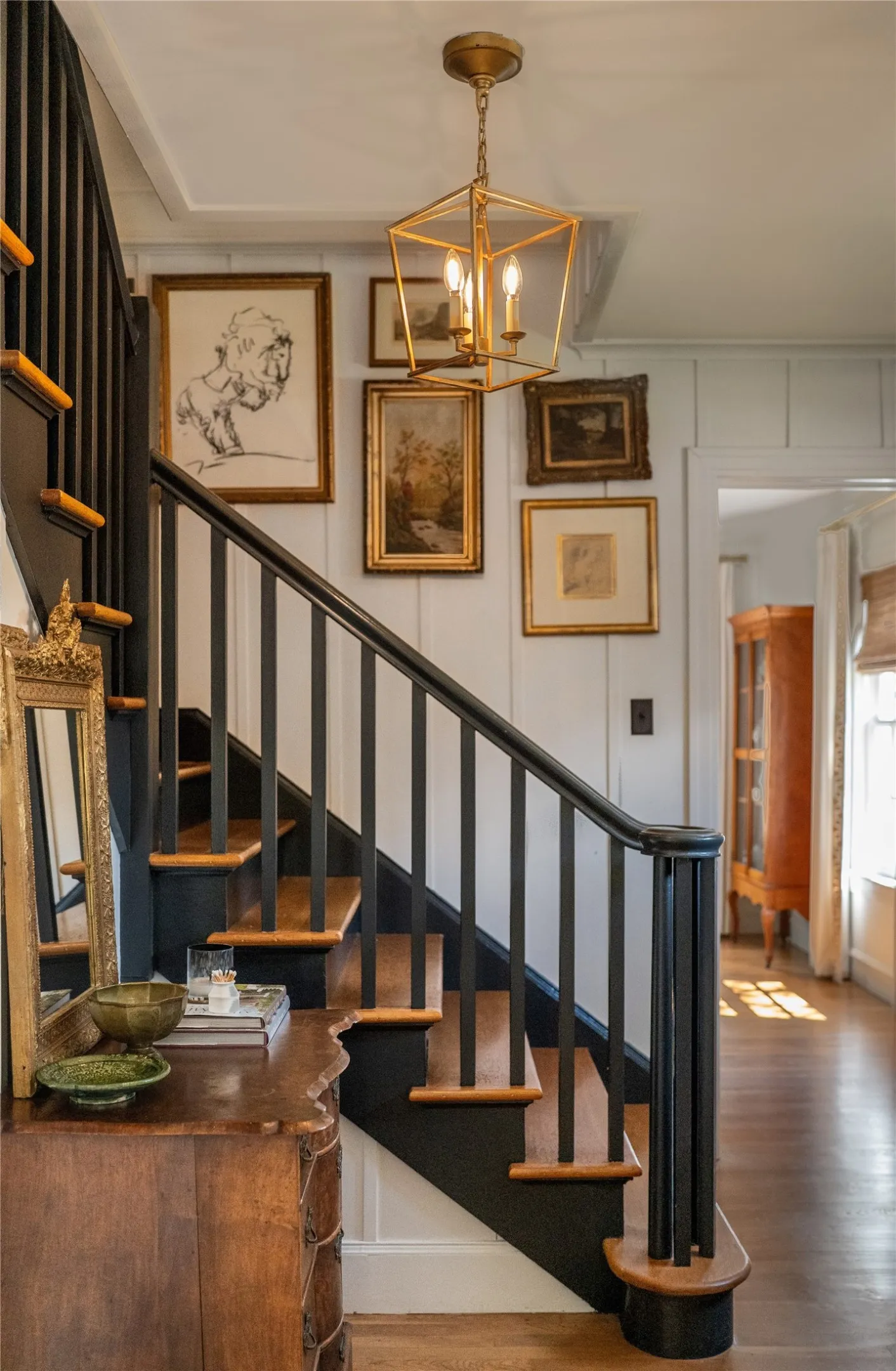 Staircase featuring dark wood risers and balusters, wood-finish treads, and a gold-tone chandelier