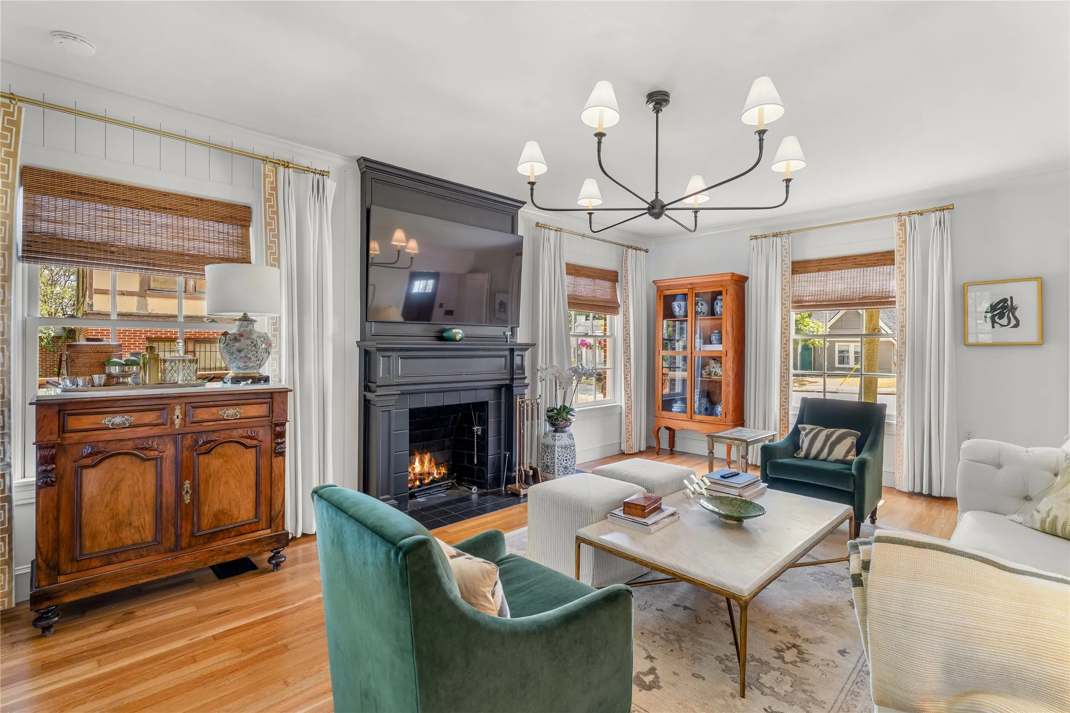 Hardwood flooring, classic fireplace, built-in shelving, sconce lighting, and a chandelier