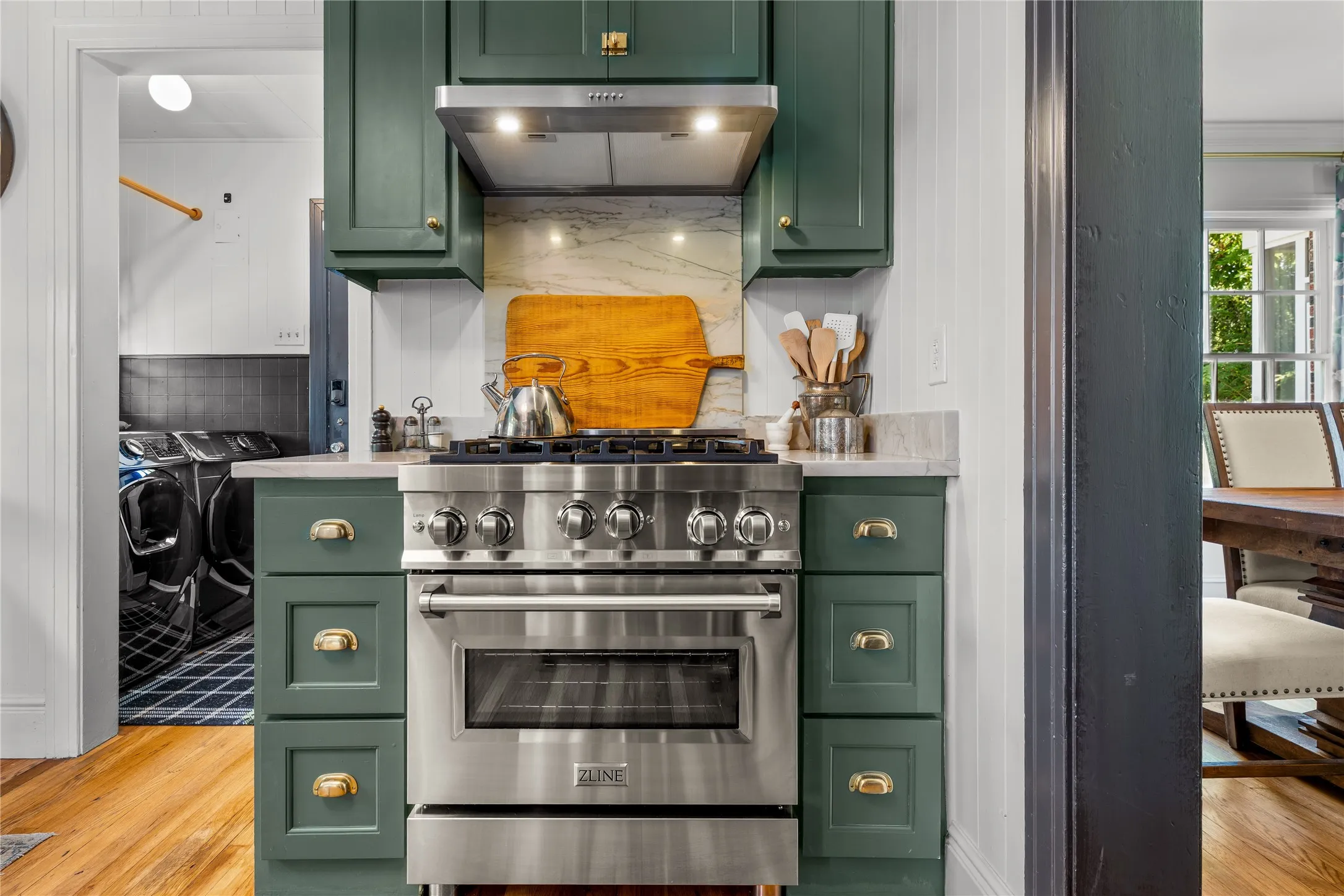 Stainless steel range with a built-in oven, green cabinetry, stone countertops, and a stone backsplash