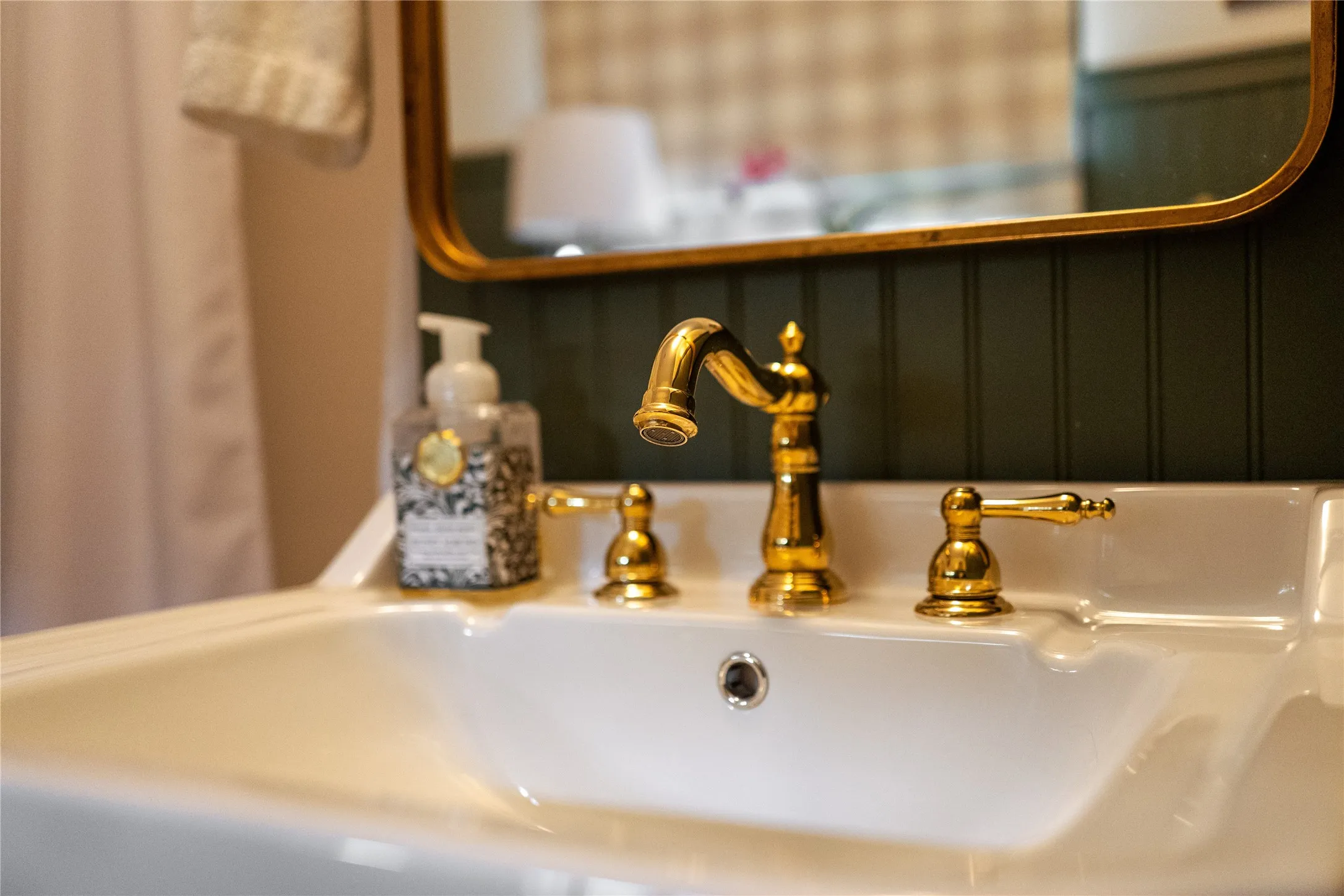 White ceramic sink with a polished brass faucet and coordinating handles