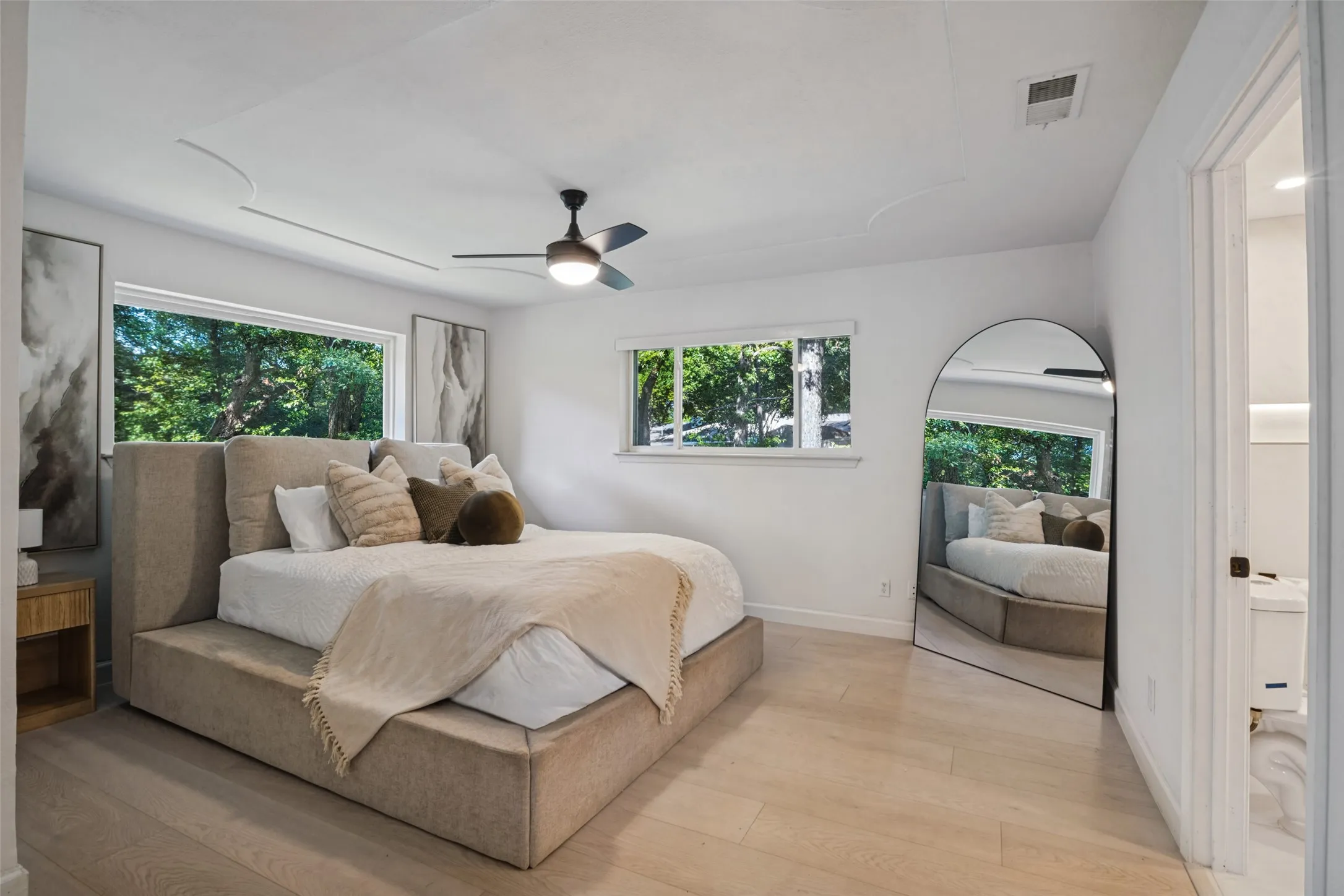 Recessed ceiling with decorative detailing, wood-finish flooring, and a ceiling fan with integrated lighting