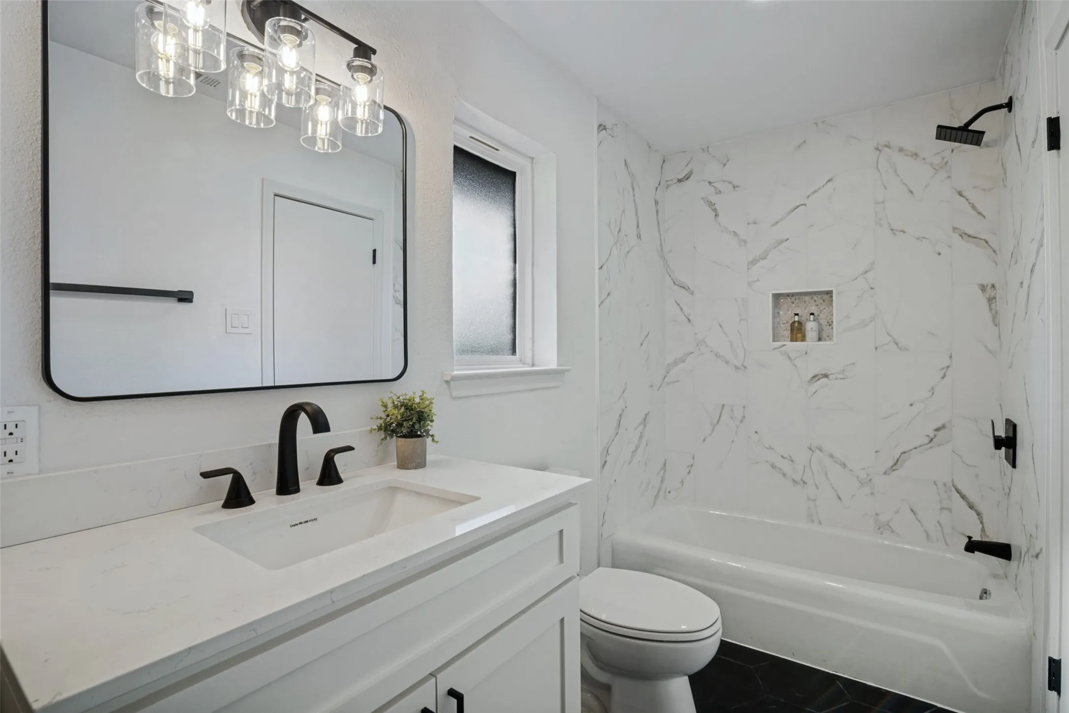 White vanity with a quartz countertop and matte black fixtures