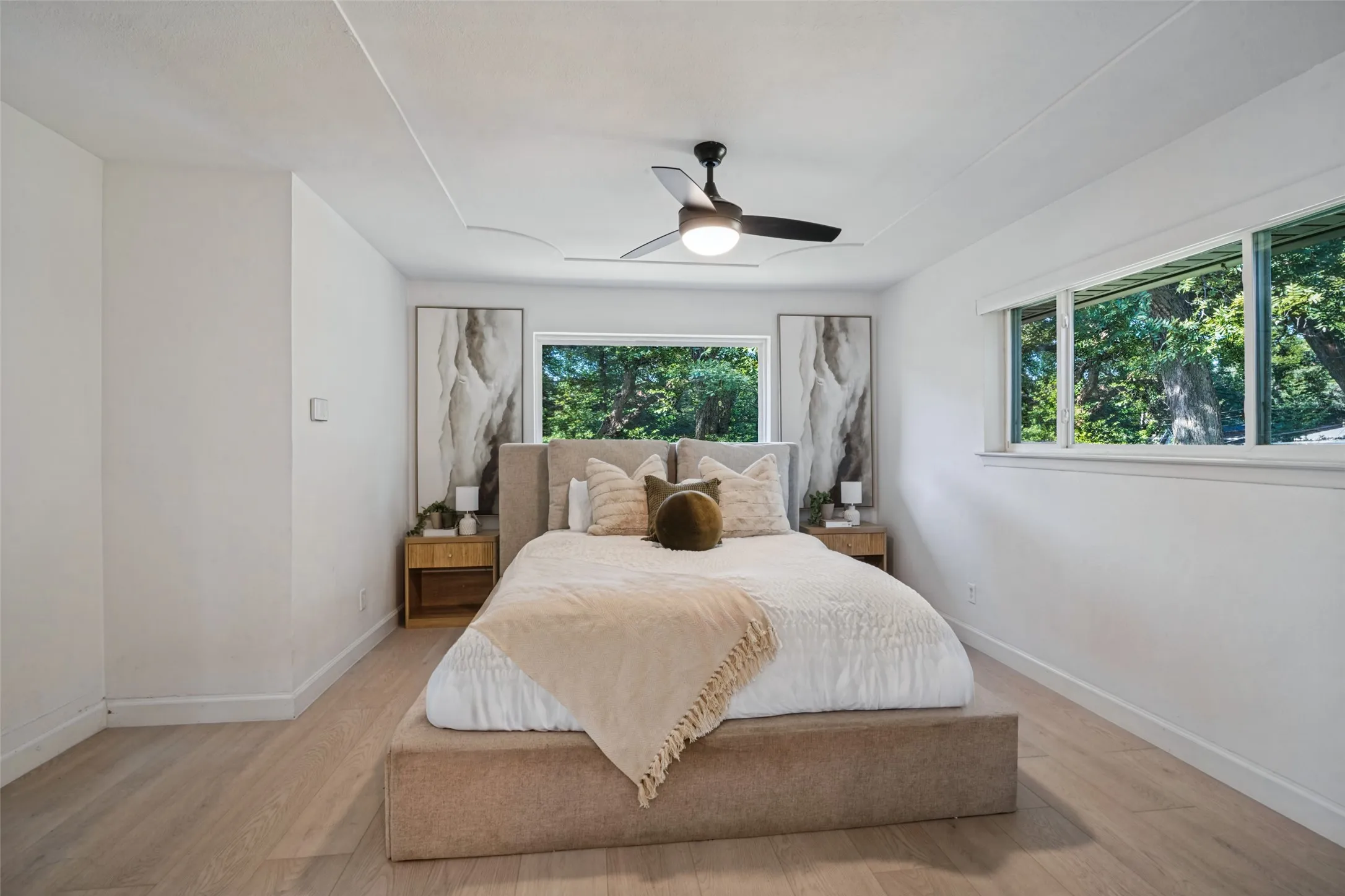 Recessed ceiling, wood-finish flooring, white walls, multiple windows, ceiling fan with integrated lighting