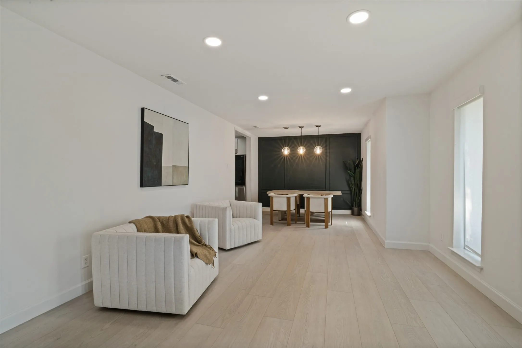 Recessed ceiling lighting, wood-finish flooring, white painted walls, and window openings