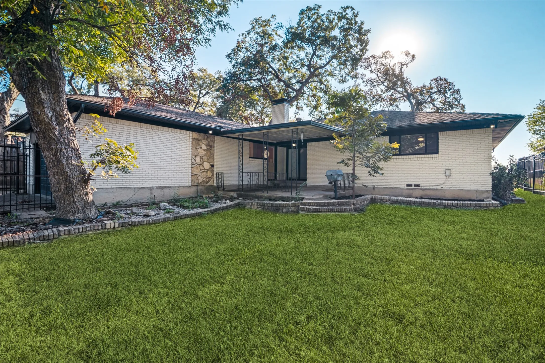 Rear exterior with a covered patio, brick and stone facade, and a tiered retaining wall