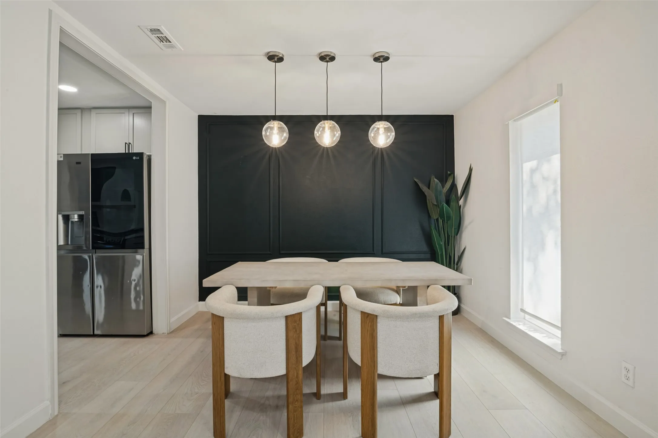 Wood-finish flooring, accent wall with decorative paneling, recessed lighting, and three globe pendant light fixtures