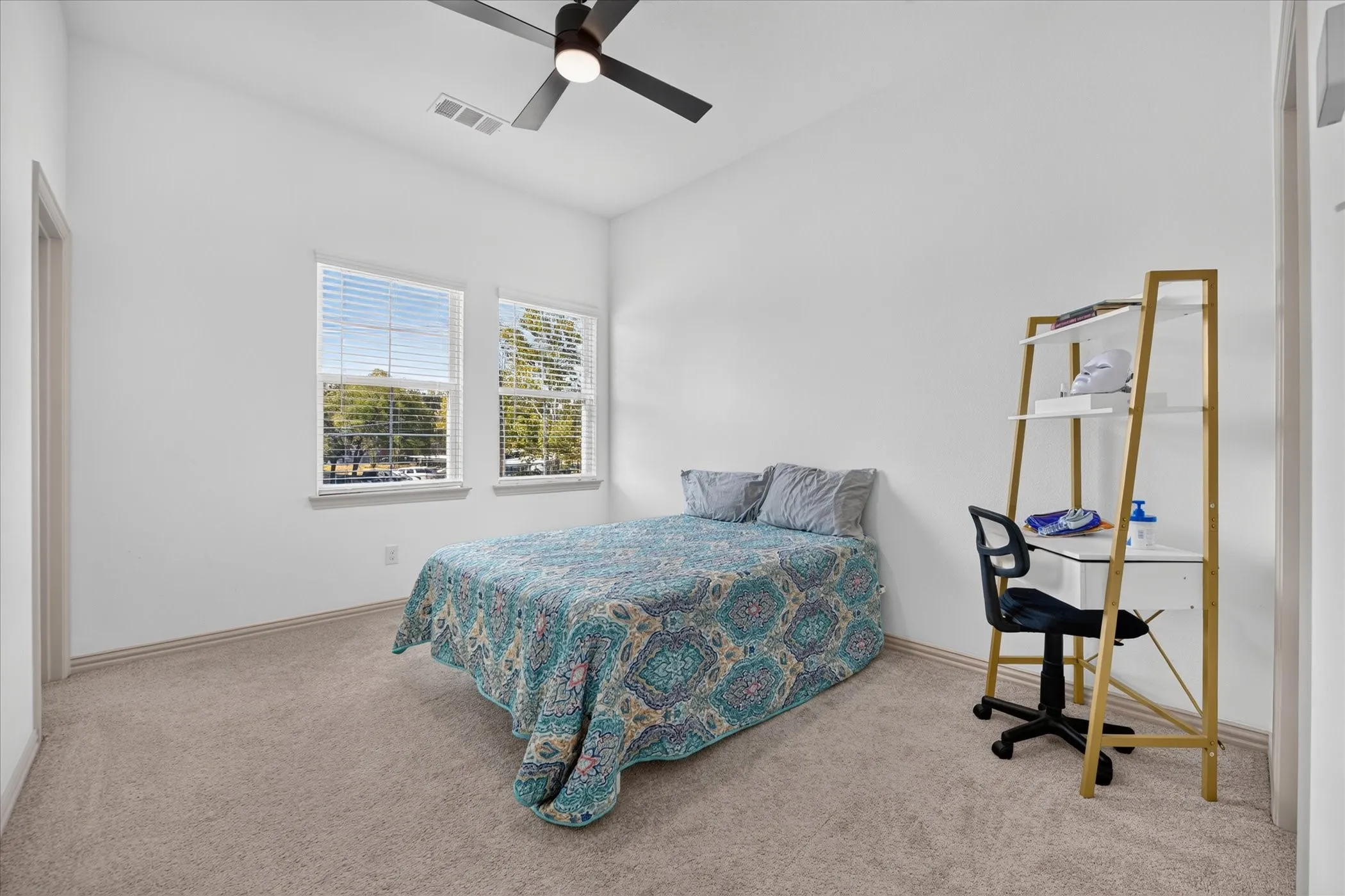 Carpeted room featuring two windows with blinds, a ceiling fan with integrated lighting, and white walls