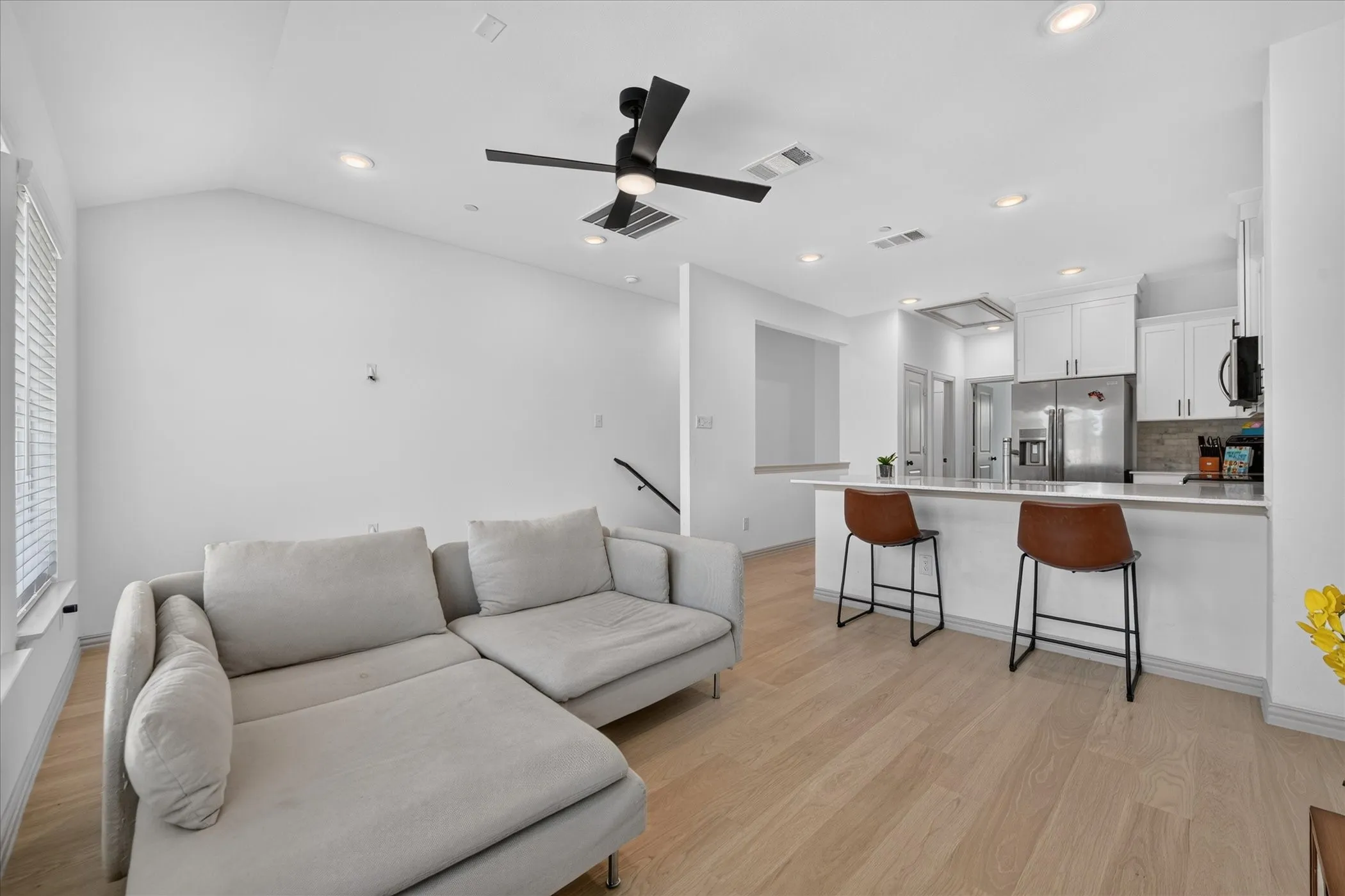 Vaulted ceiling with recessed lighting, wood-finish flooring, and a contemporary ceiling fan