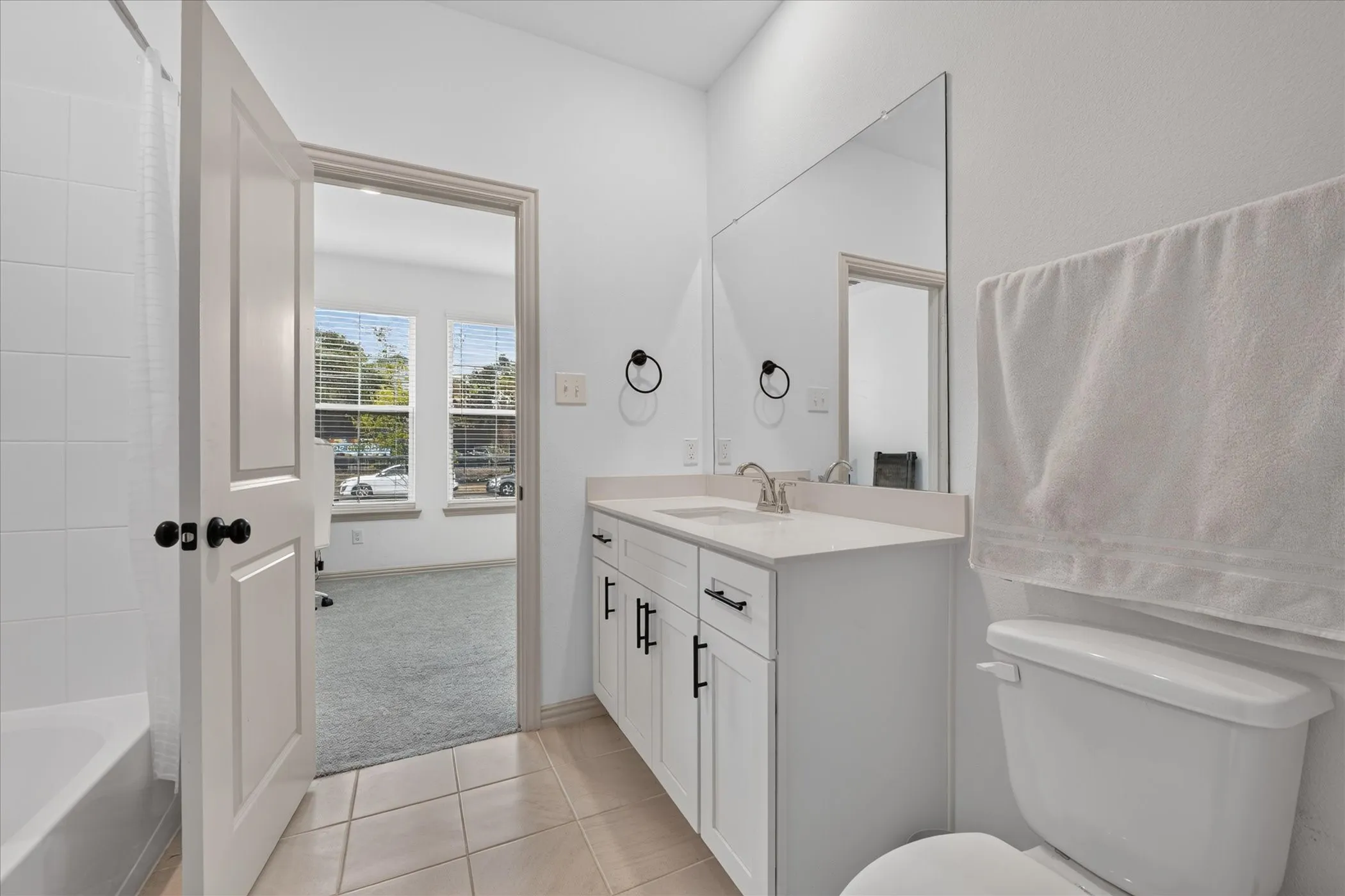 White vanity with a neutral countertop, undermount sink, and matte black hardware