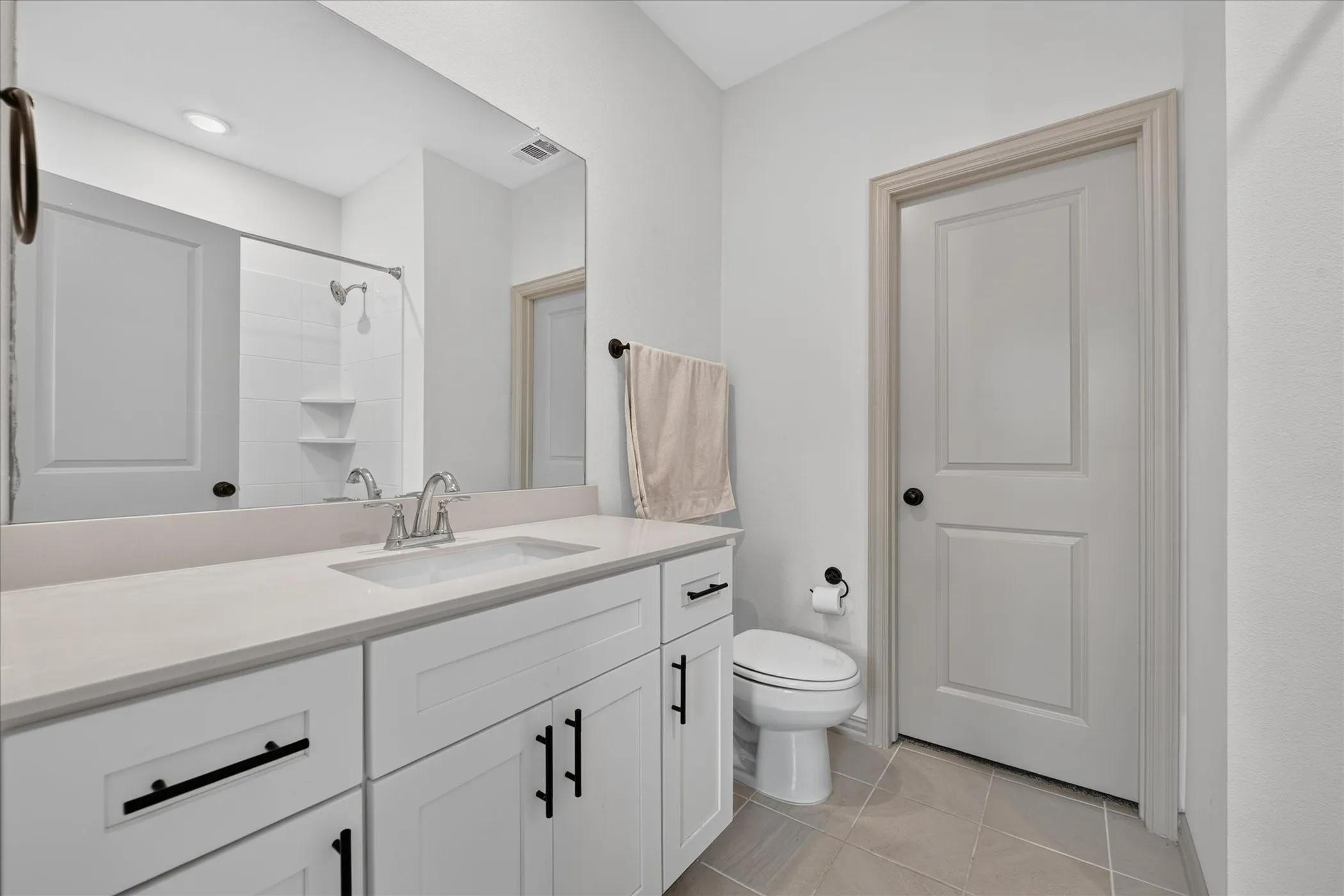 White shaker-style vanity with matte black hardware, light-toned countertop, and undermount sink