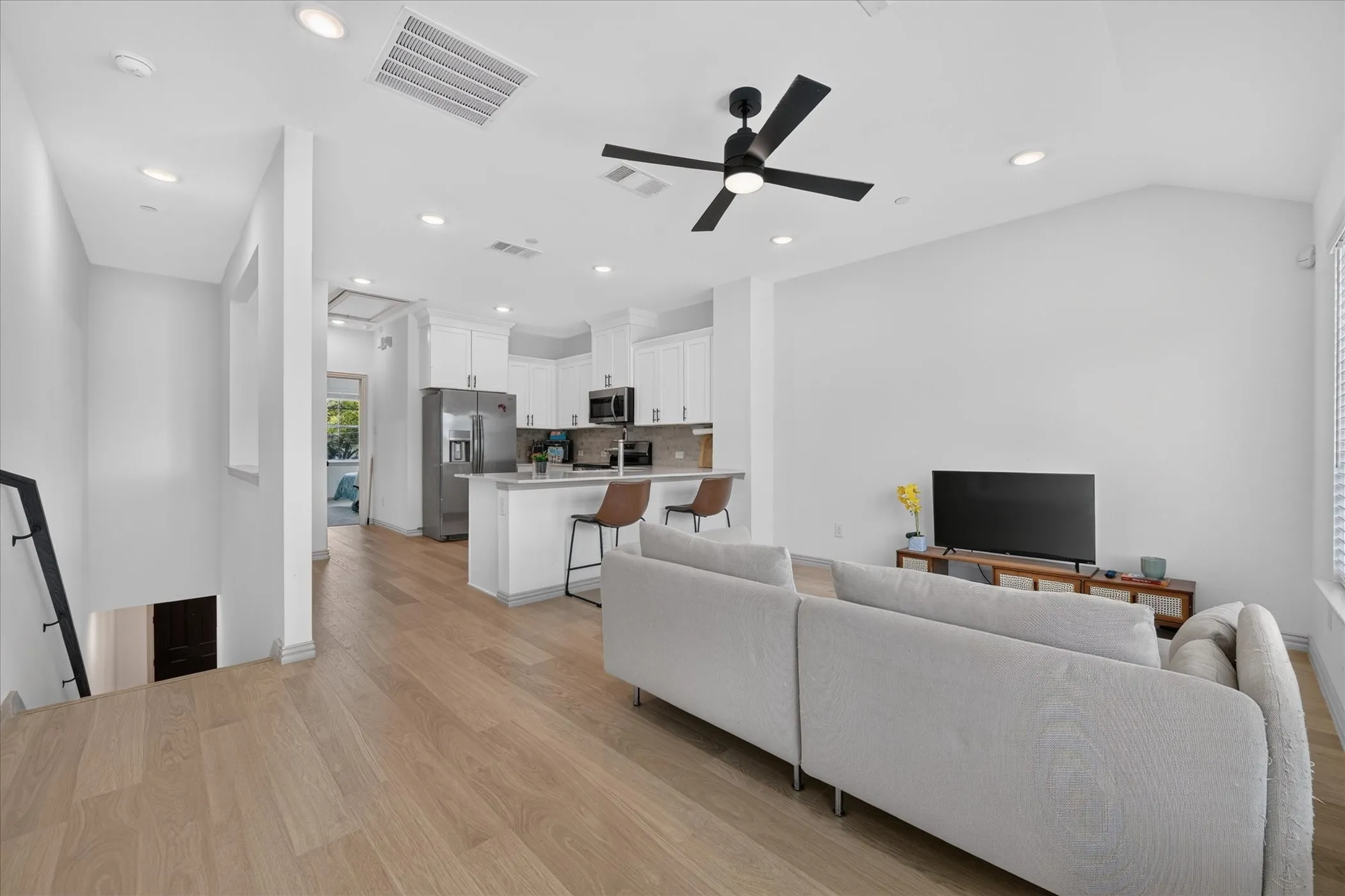 Open-concept living area with wood-finish flooring, vaulted ceiling, and recessed lighting