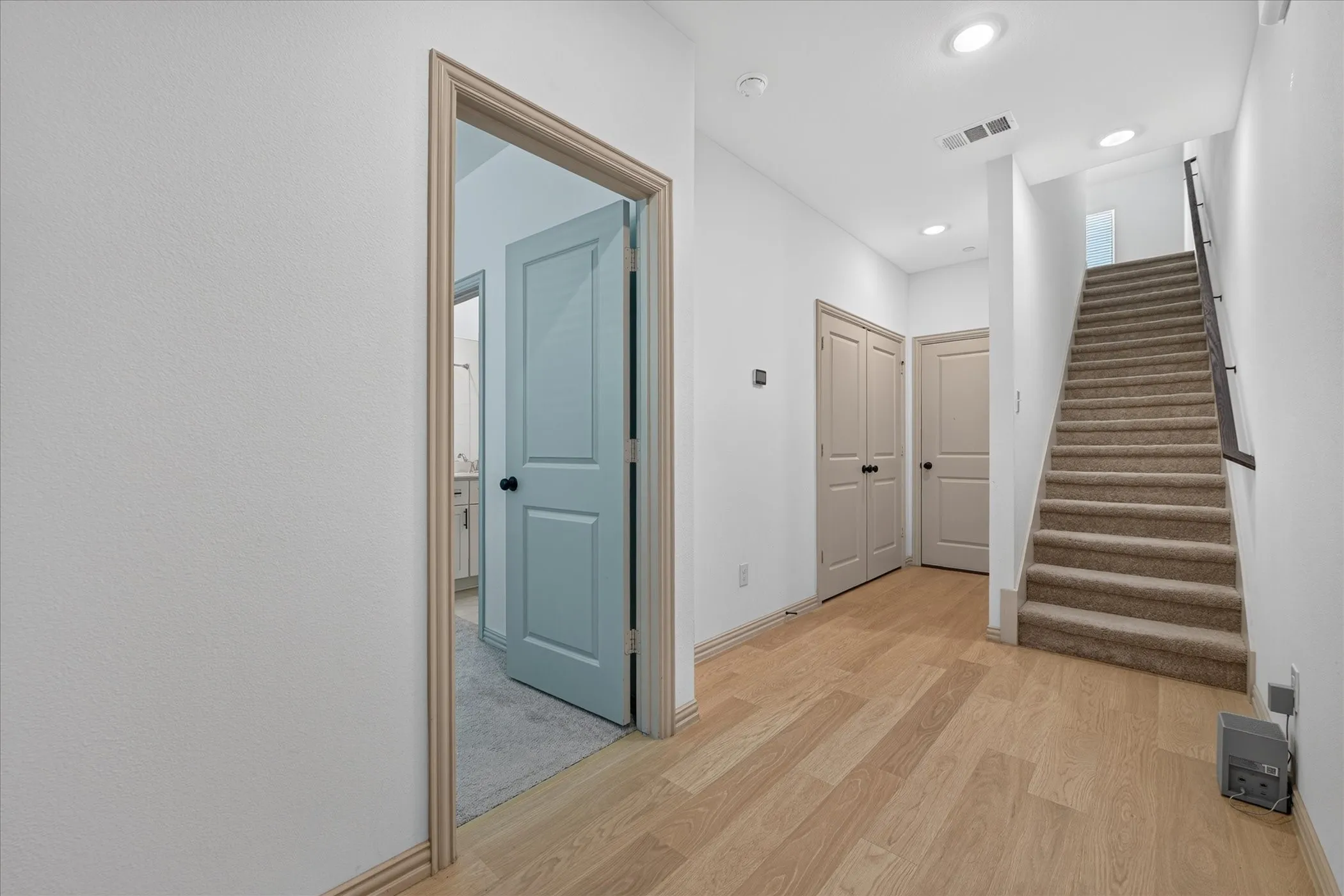 Light wood-finish flooring, recessed lighting, carpeted staircase, and neutral wall tones