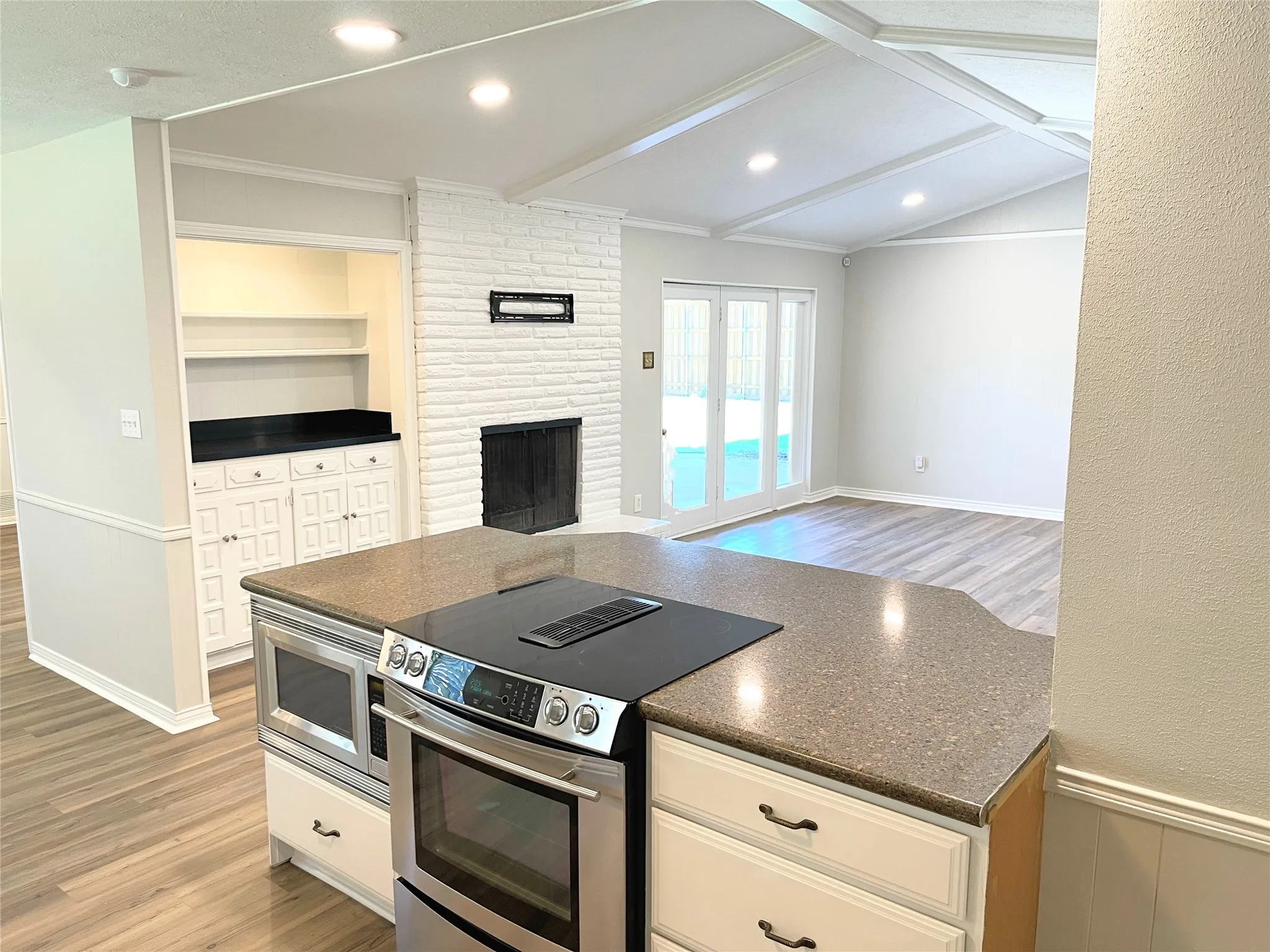 Kitchen with ornamental molding, light wood-type flooring, white cabinetry, and appliances with stainless steel finishes
