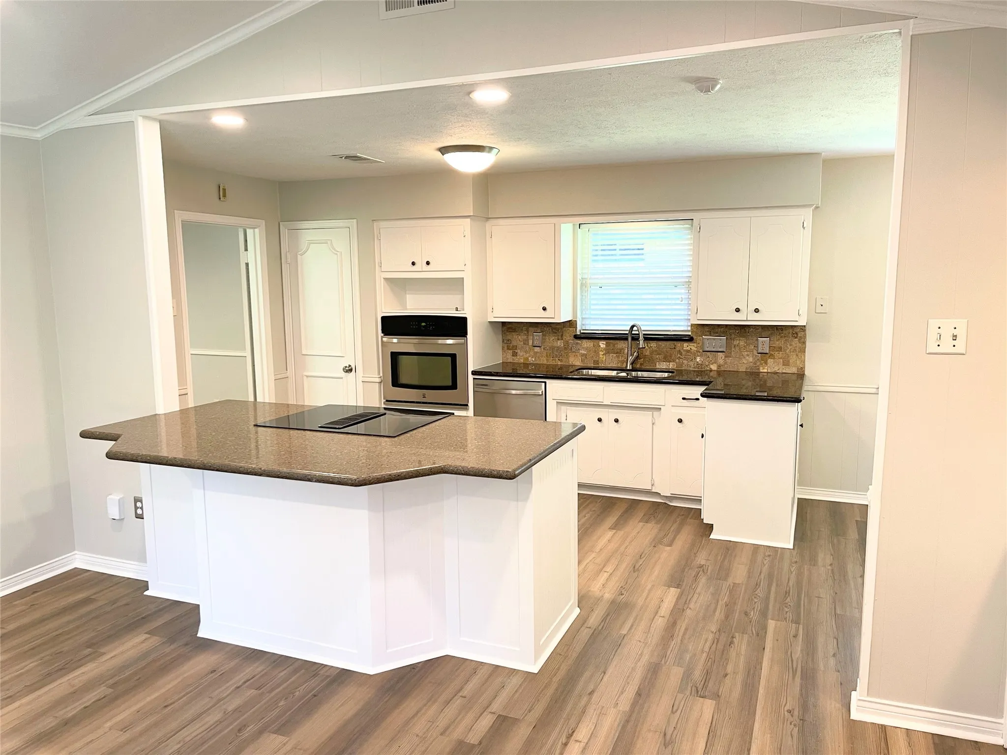 Kitchen featuring sink, white cabinetry, appliances with stainless steel finishes, hardwood / wood-style floors, and crown molding