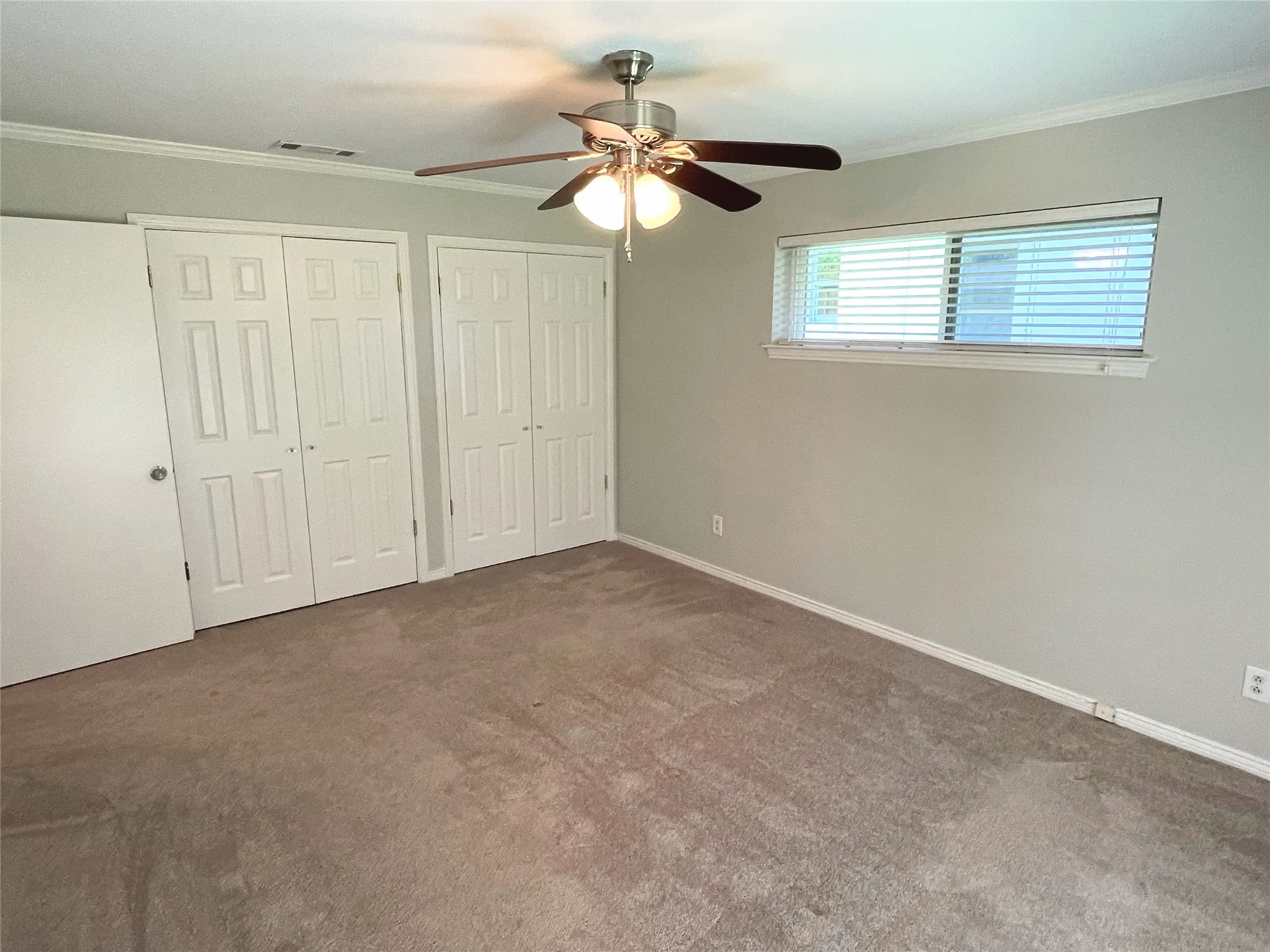 Bedroom 3 with carpet, ornamental molding, ceiling fan, and multiple closets