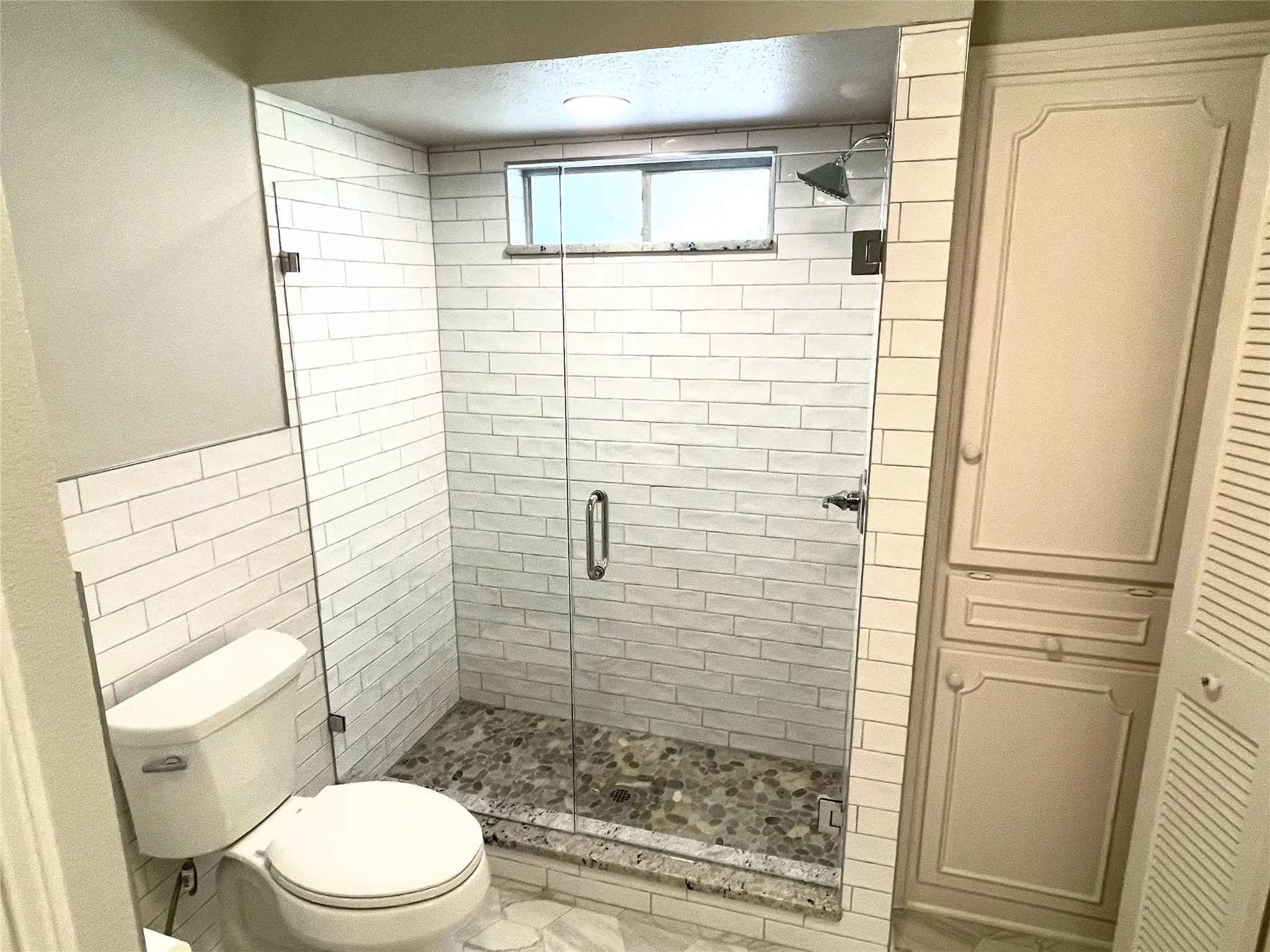 Primary Ensuite Bathroom with tile walls, a shower with door, and toilet