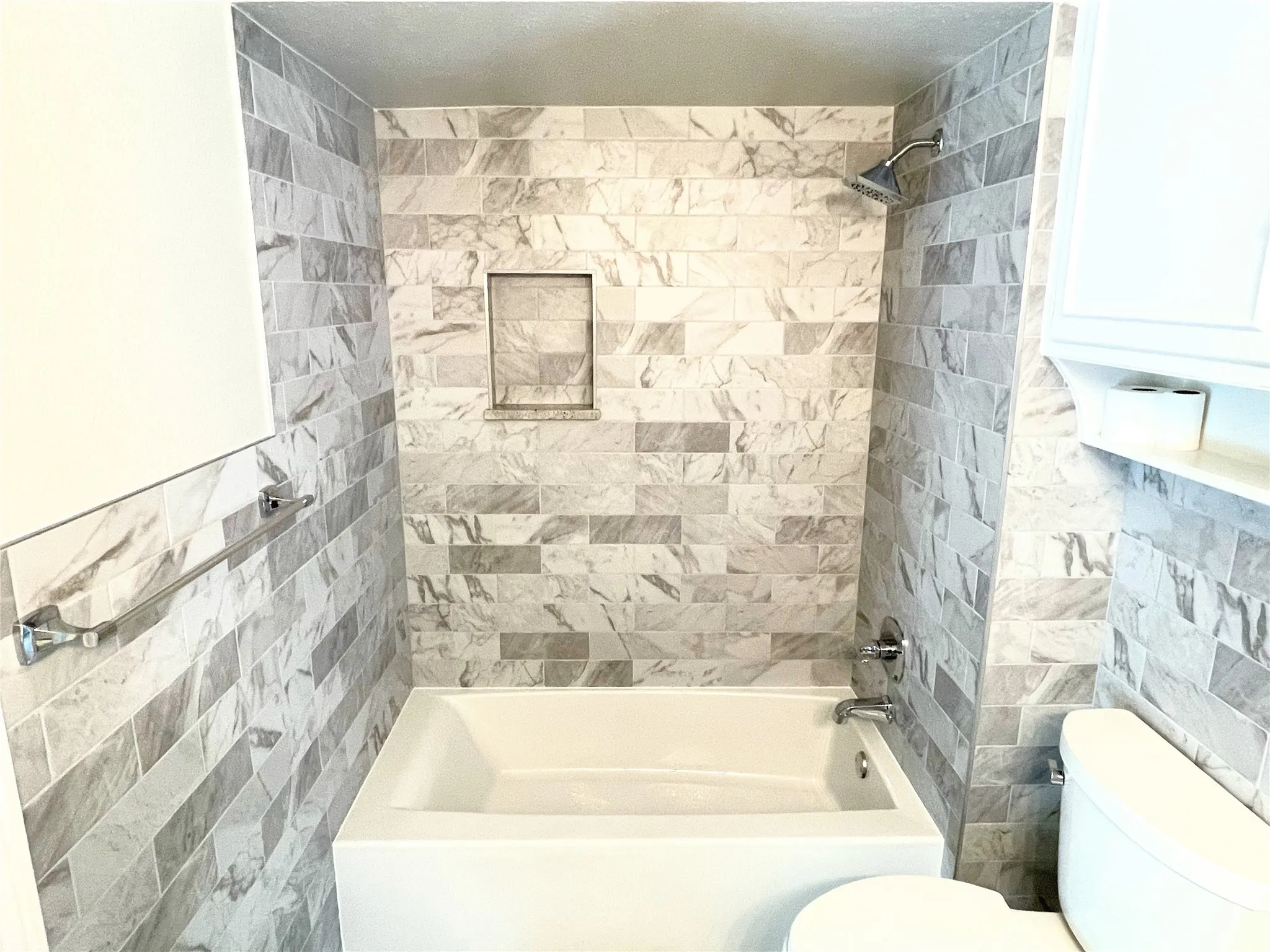 Jack and Jill Bathroom featuring tiled shower / bath, tile walls, and toilet