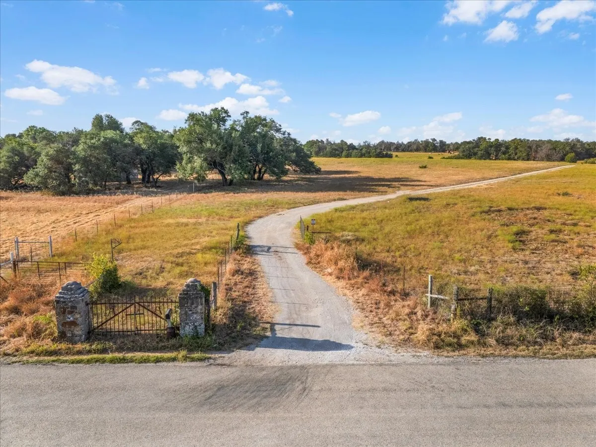 Gated entry leading to expansive open land with mature trees