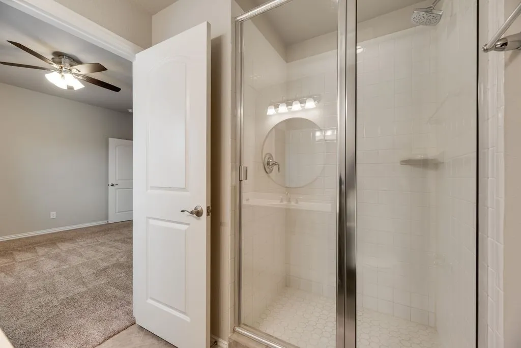 Glass-enclosed shower with white subway tile, hexagonal floor tiles, and a built-in shower shelf