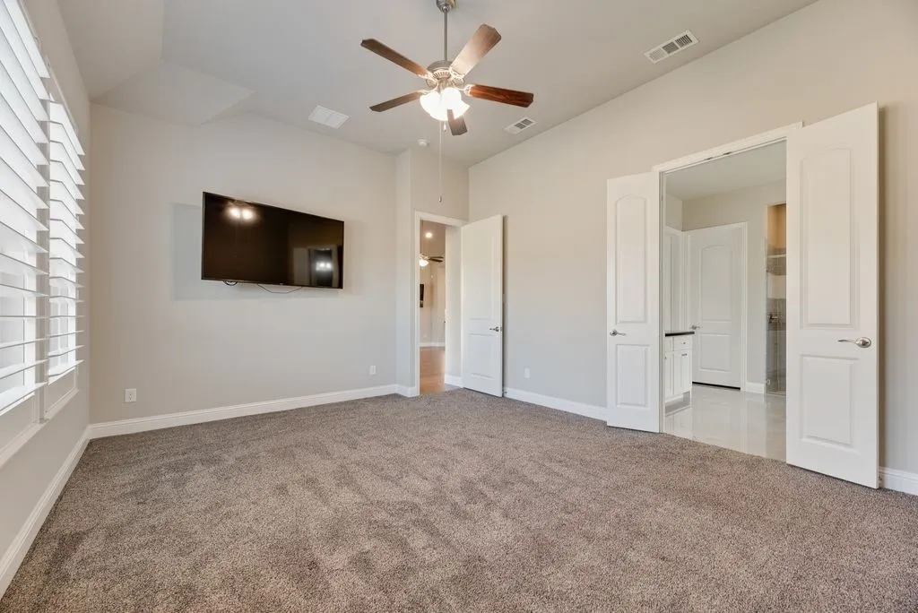Vaulted ceiling with a ceiling fan, carpeted flooring, window with plantation shutters, and double doors