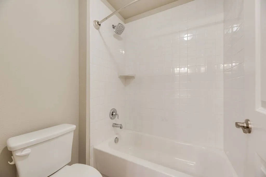 White subway tile shower surround with integrated corner shelving and chrome fixtures