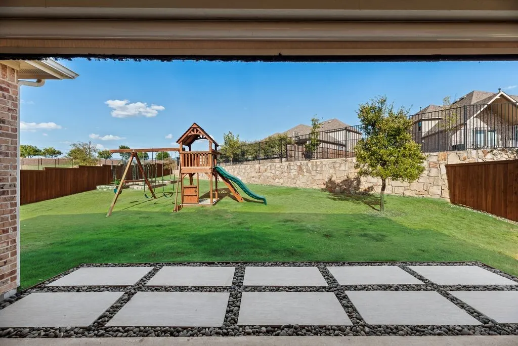 Concrete paver patio with river rock accents, expansive lawn, and wood privacy fencing