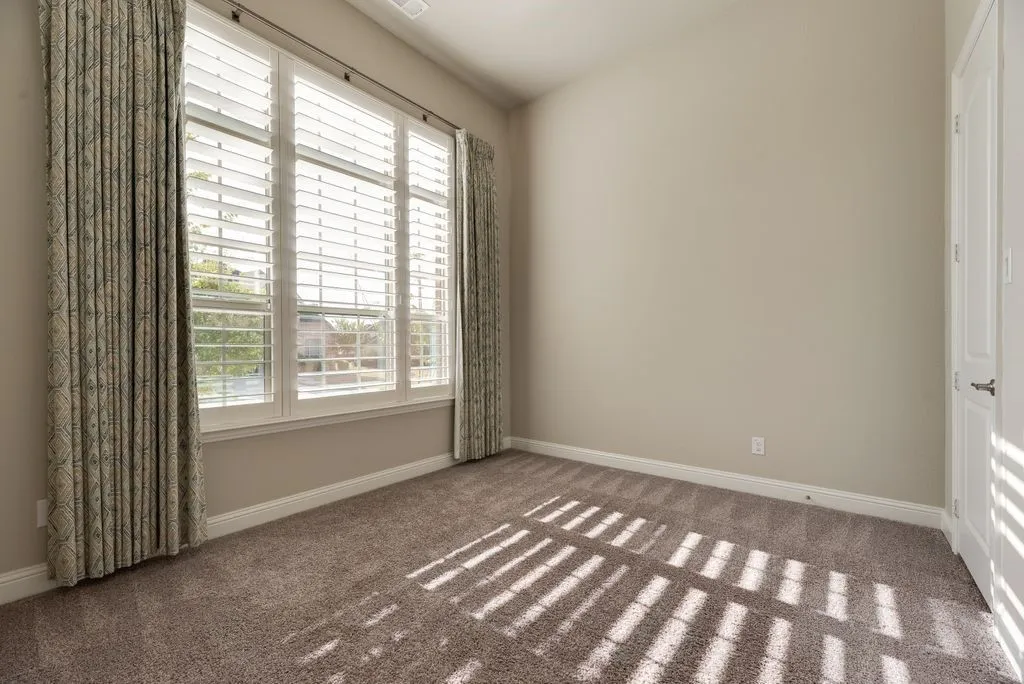Wall-to-wall carpeting, white trim, recessed lighting, and a window with plantation shutters