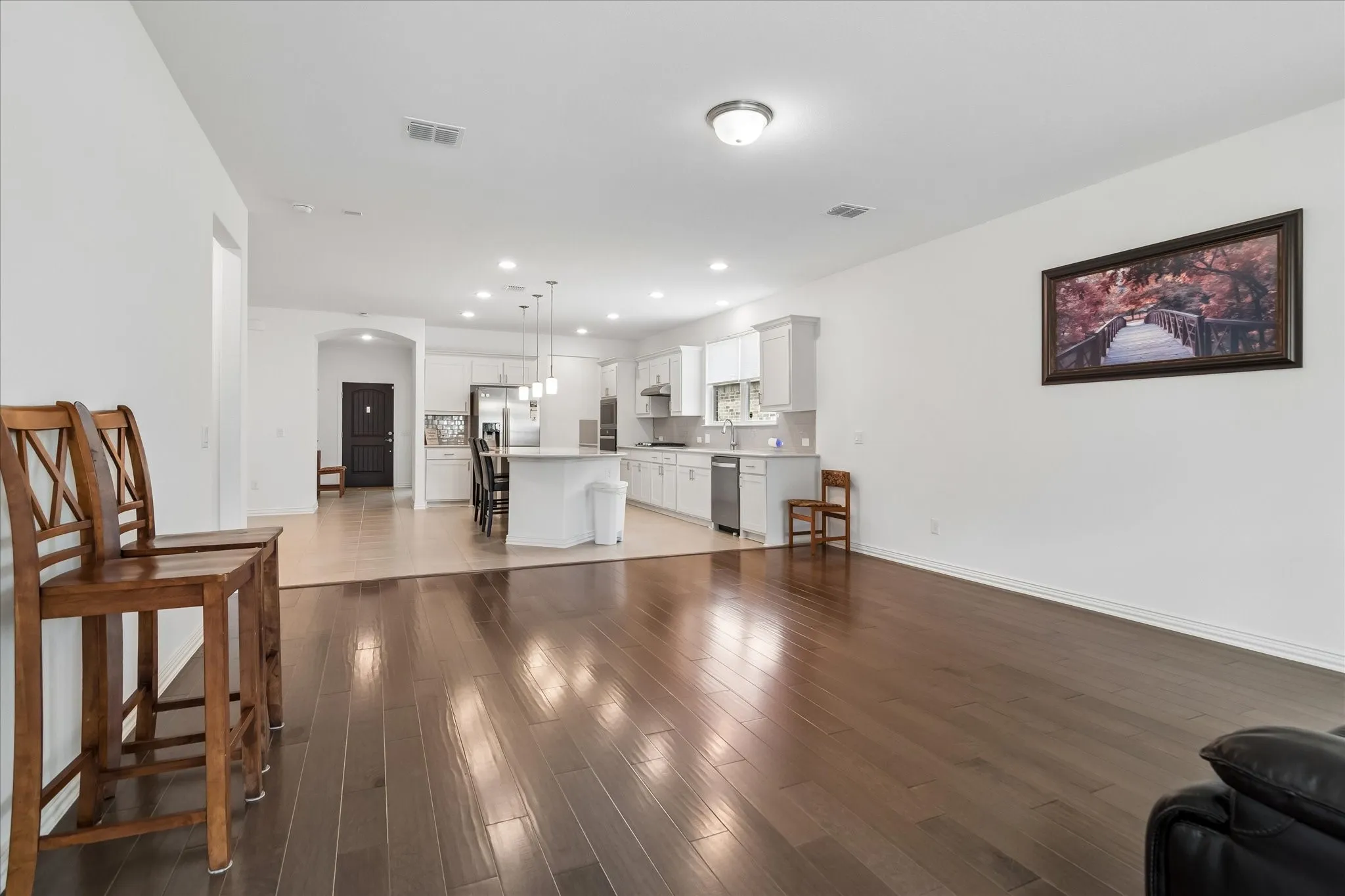 Hardwood-finish flooring, white walls, recessed lighting, contemporary kitchen cabinetry, and stainless steel appliances