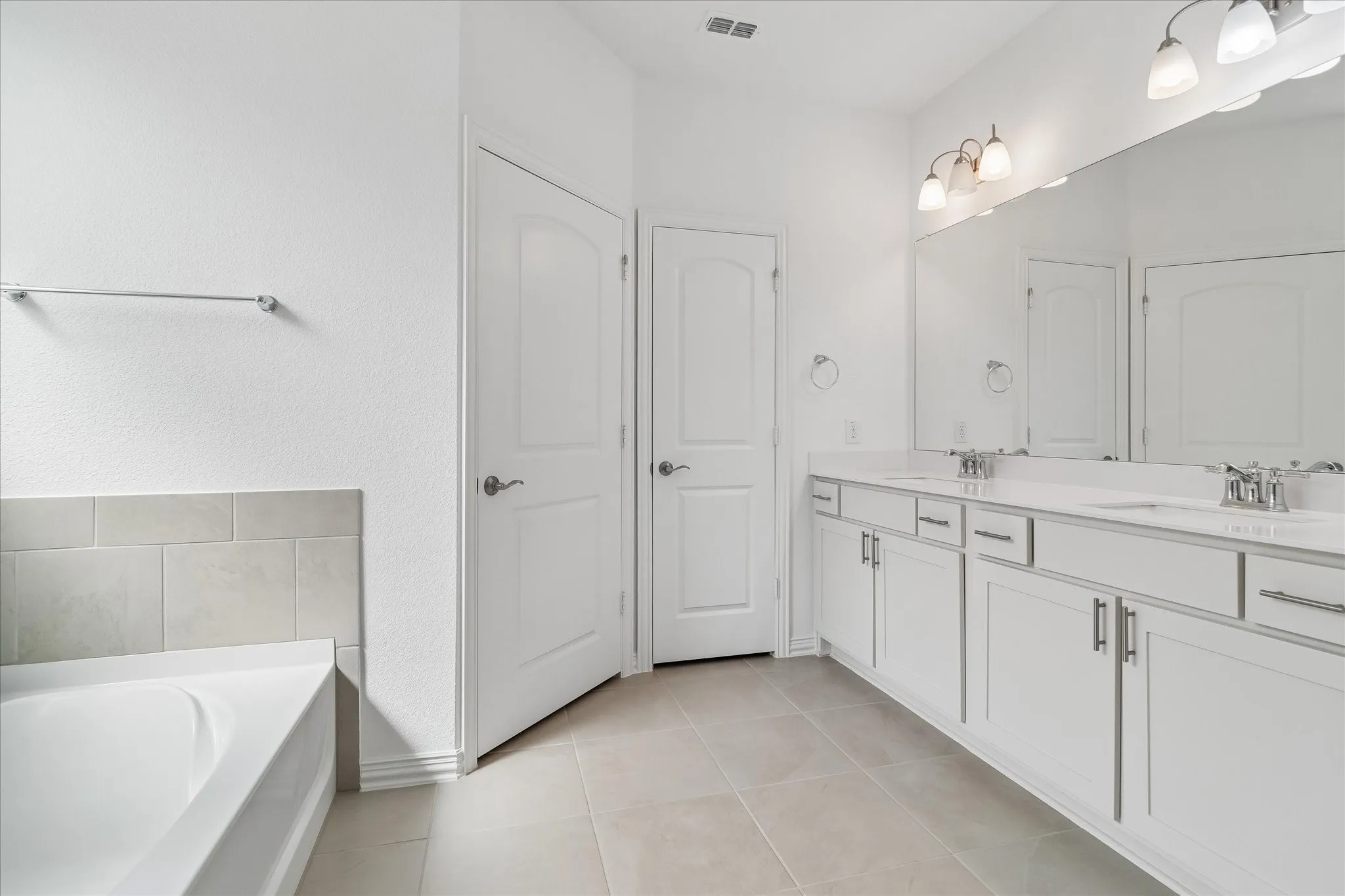 Dual vanity with integrated sinks, full-width mirror, and overhead lighting
