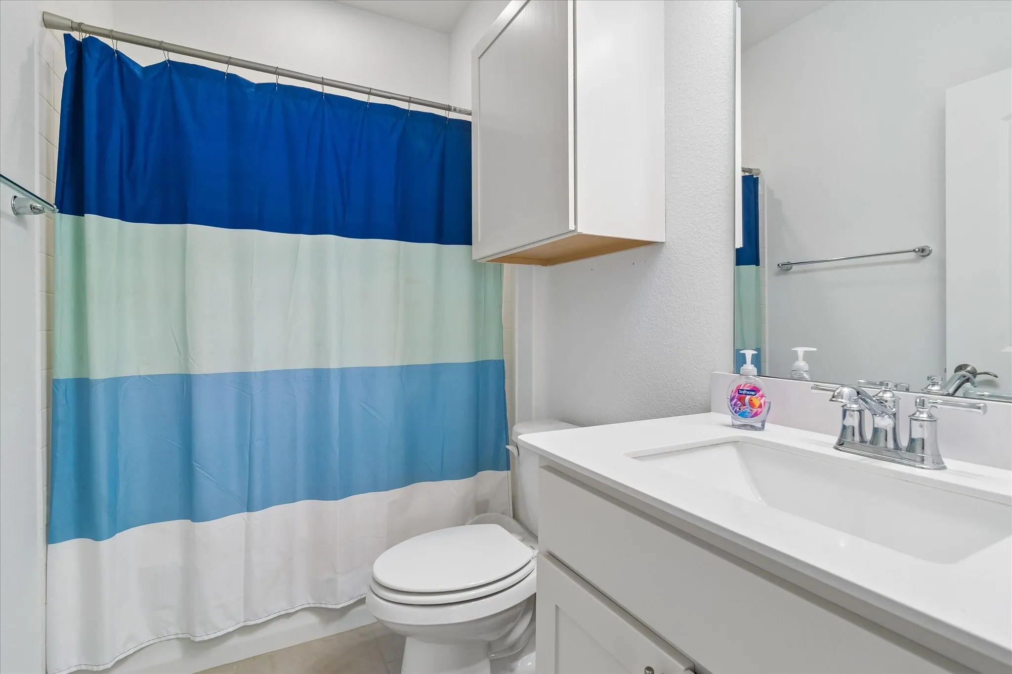 White vanity with integrated sink, chrome faucet, and mirrored wall