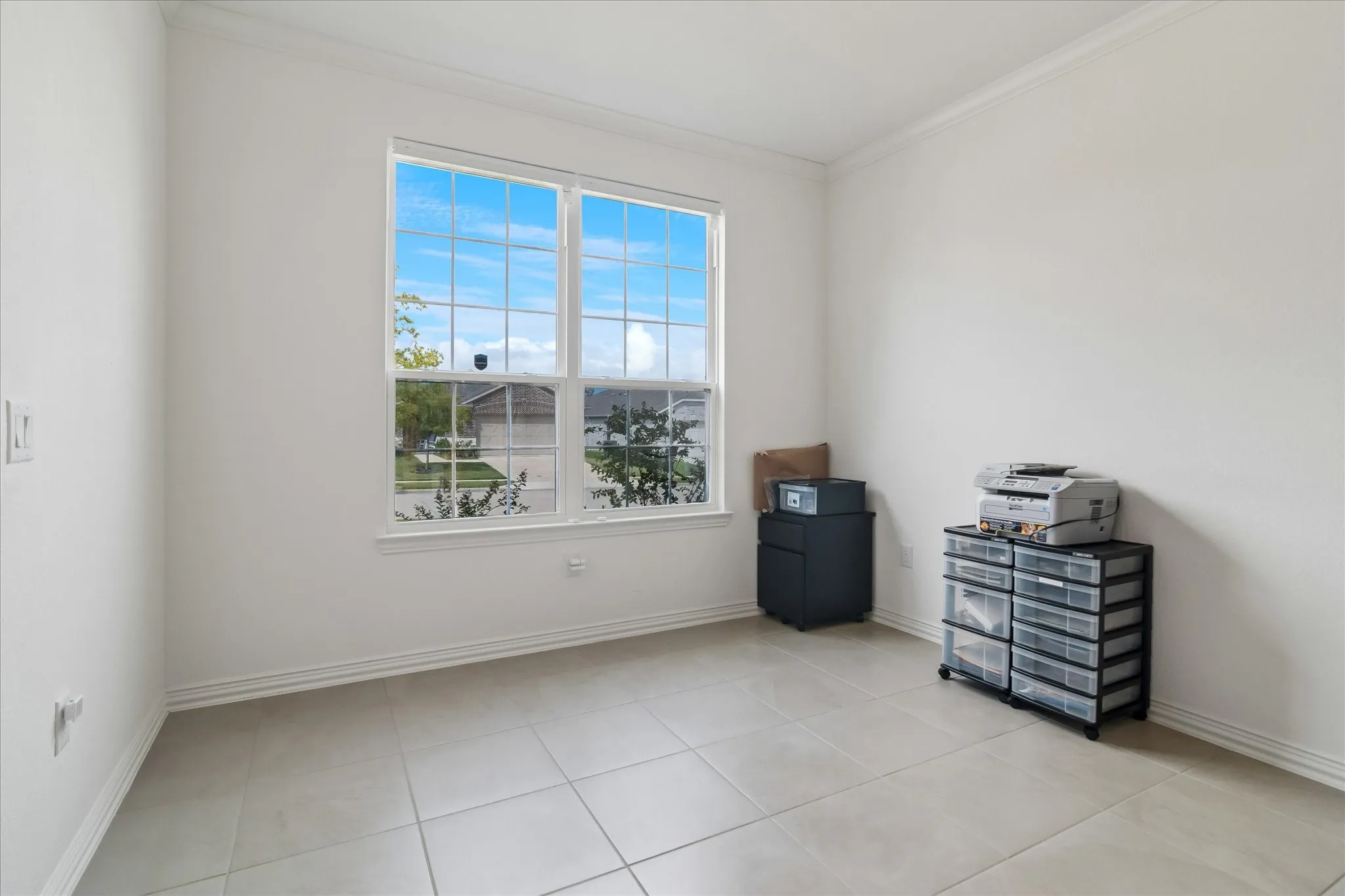 Large multi-pane window, tile flooring, white walls, and crown molding