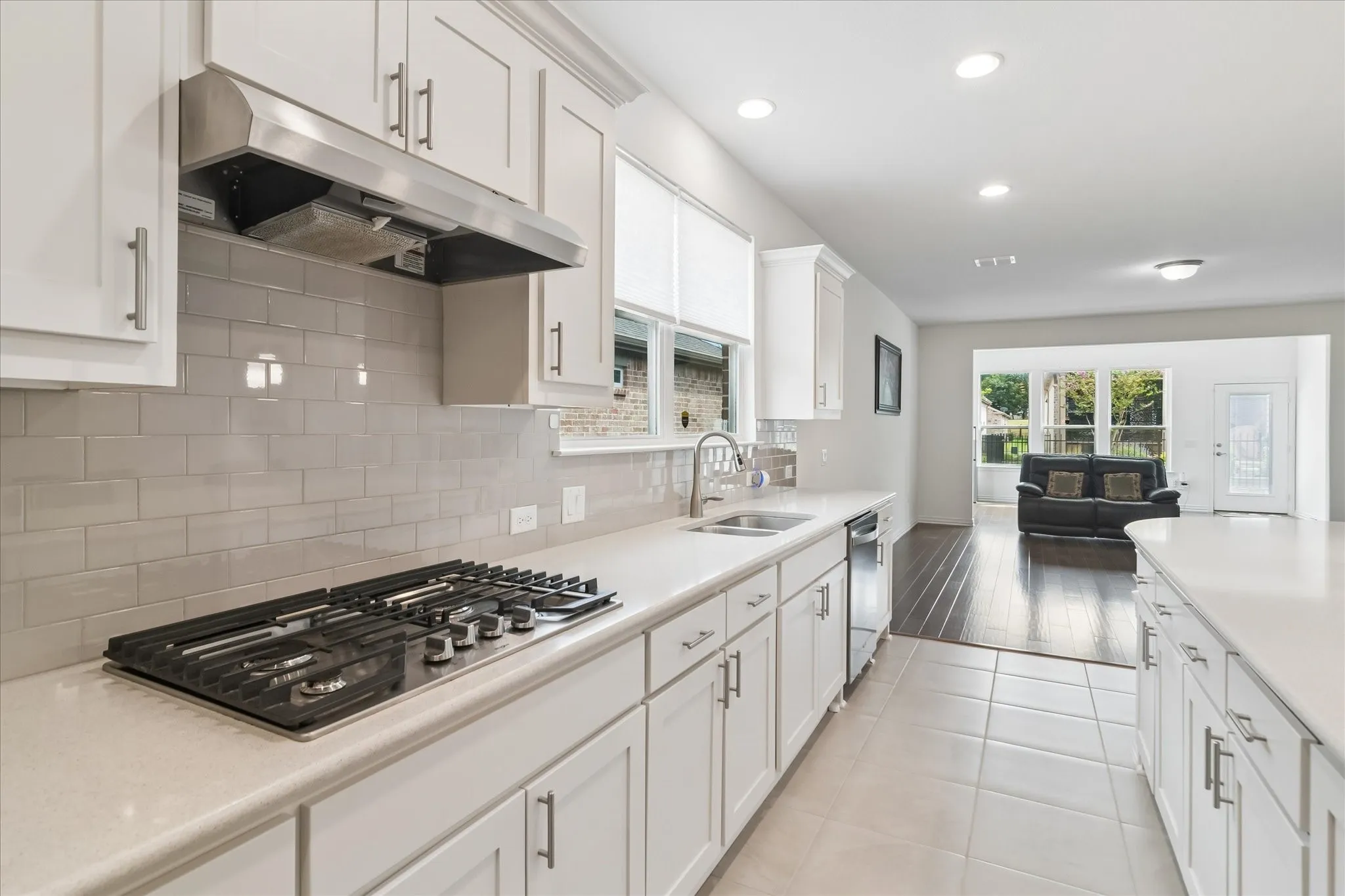 Kitchen featuring white cabinetry, light-colored countertops, a gas cooktop, and a subway tile backsplash