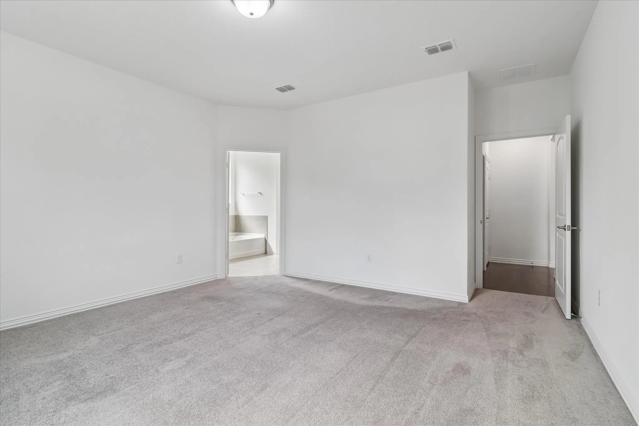 Spacious room featuring light gray carpeting and bright white walls