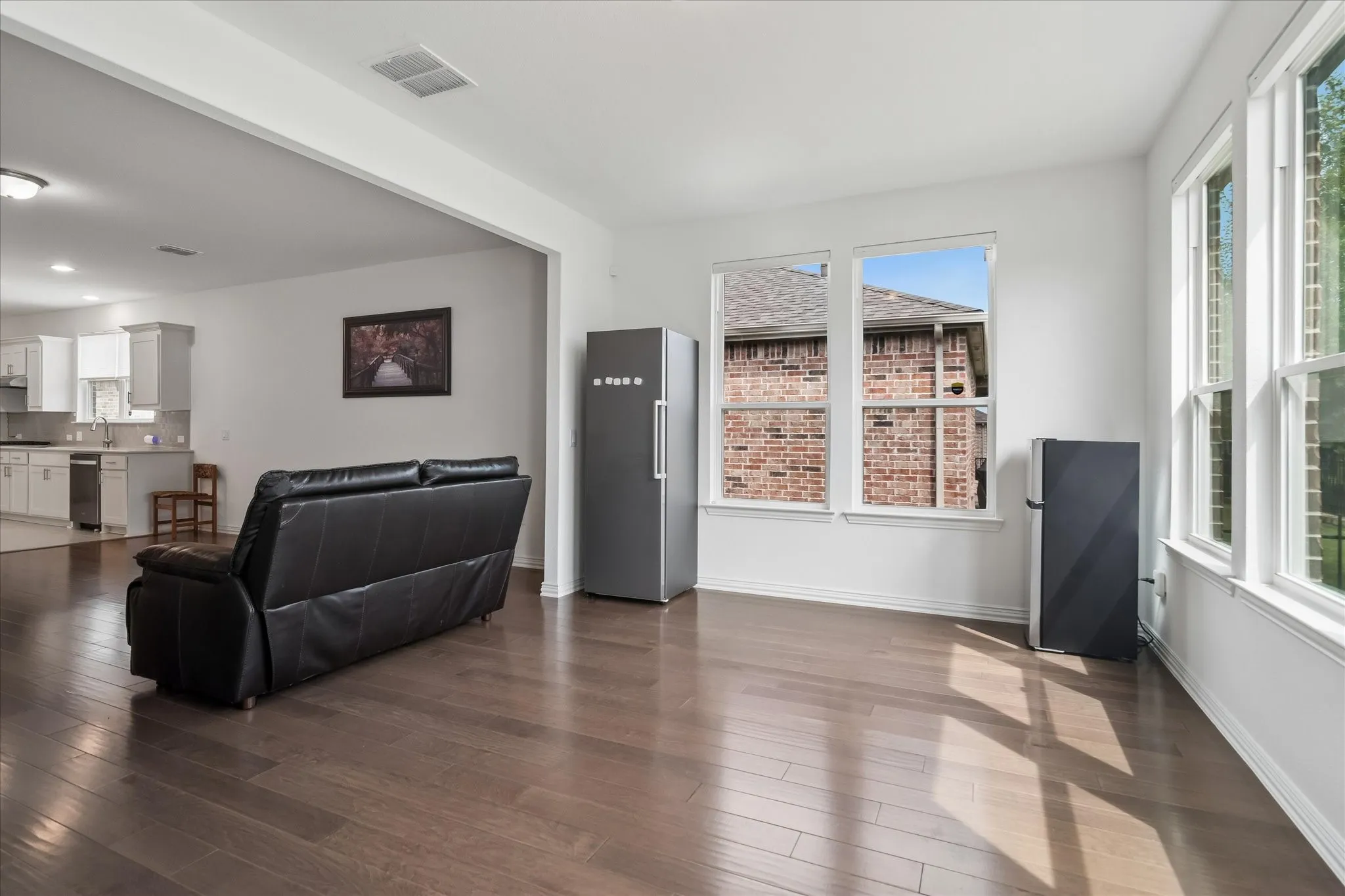Wood-finish flooring throughout, white walls, and multiple large windows