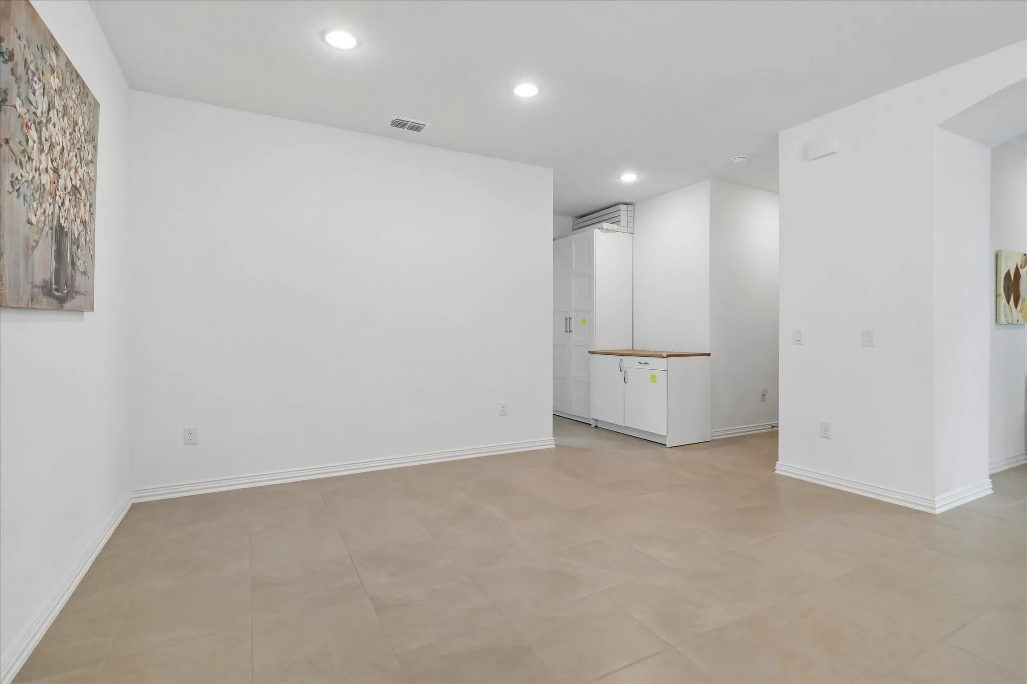 Spacious room featuring neutral-toned tile flooring, recessed lighting, and crisp white walls