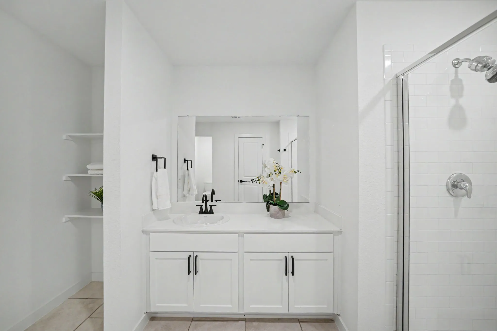 White shaker-style vanity with a single basin sink and stone-finish countertop