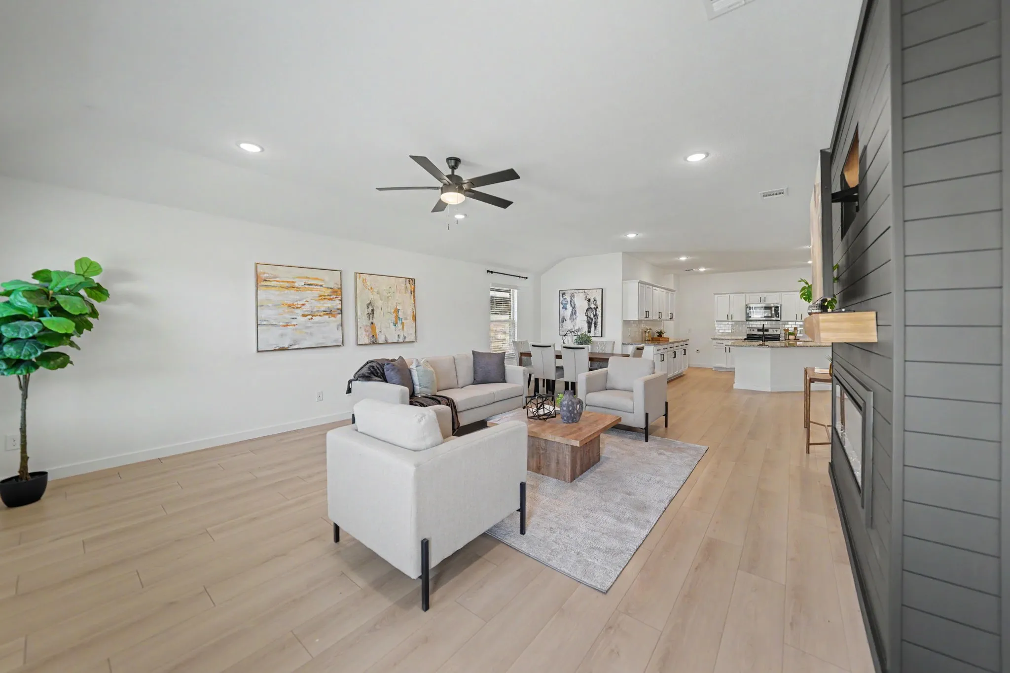 Recessed lighting, wood-finish flooring, a contemporary ceiling fan, and a built-in fireplace with a dark paneled surround and natural wood mantle