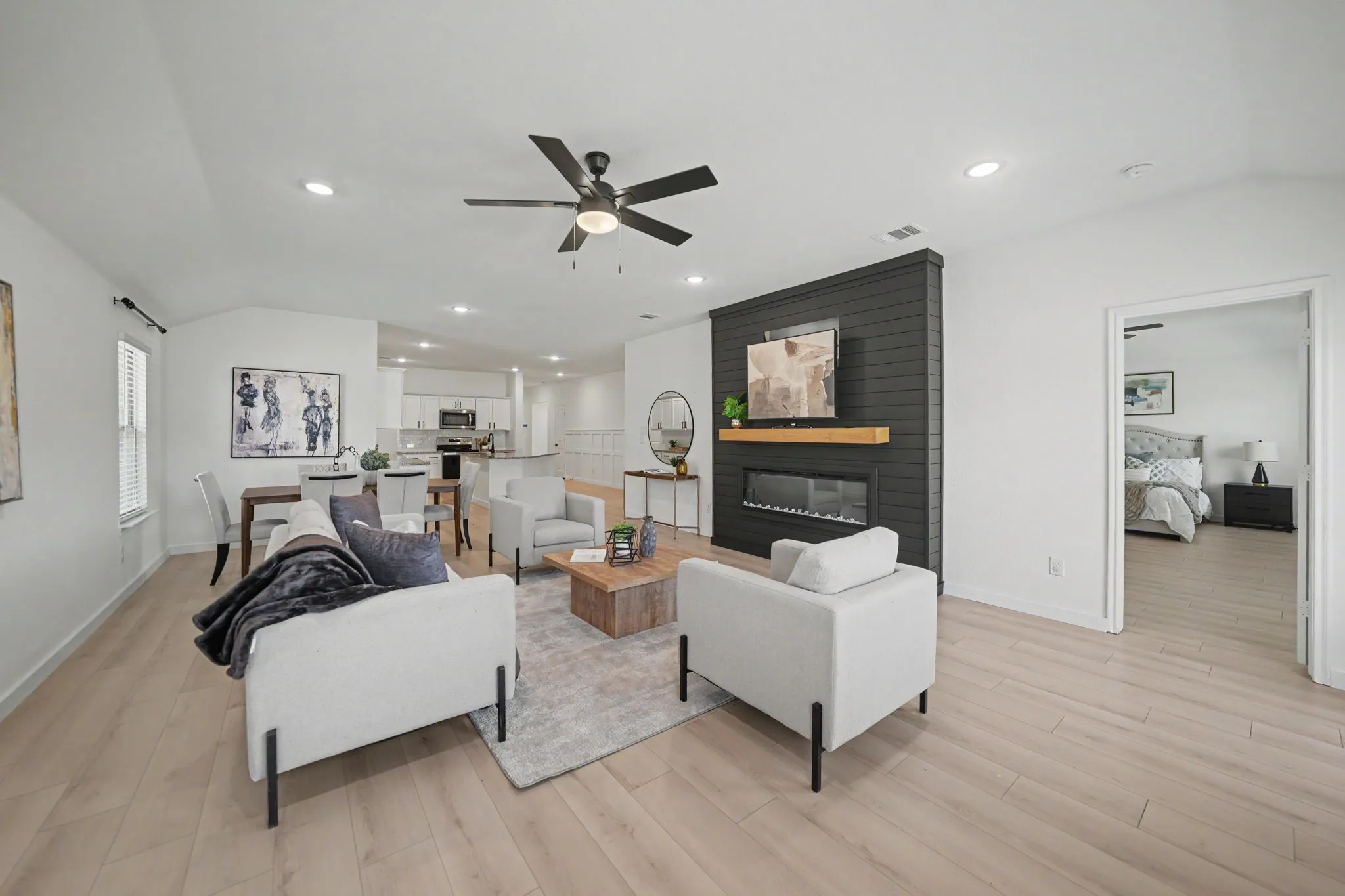 Recessed lighting, wood-finish flooring, a contemporary ceiling fan, and a built-in fireplace with a dark paneled surround and natural wood mantle