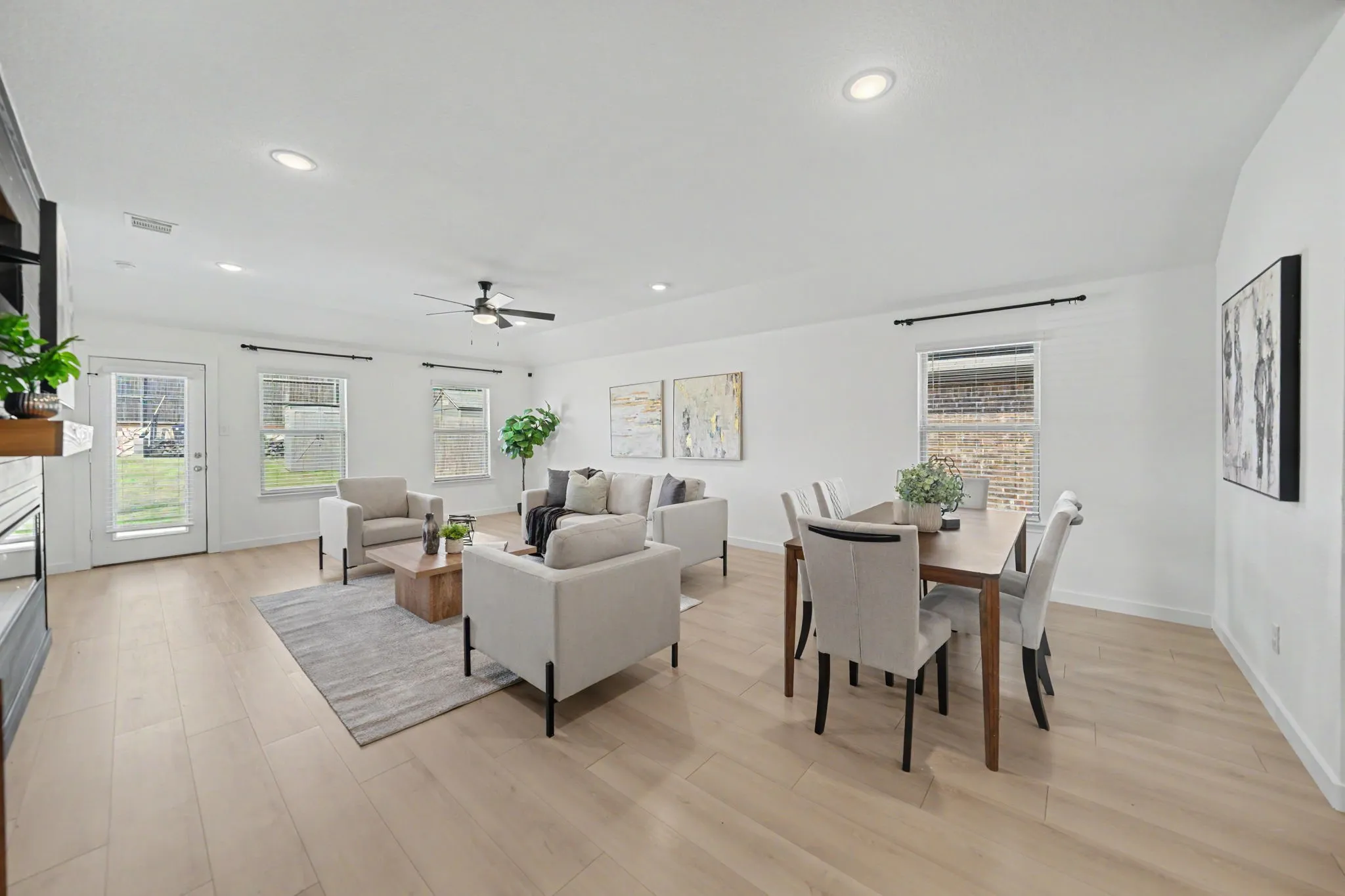 Open-concept living area with light wood-finish flooring, recessed lighting, and a ceiling fan