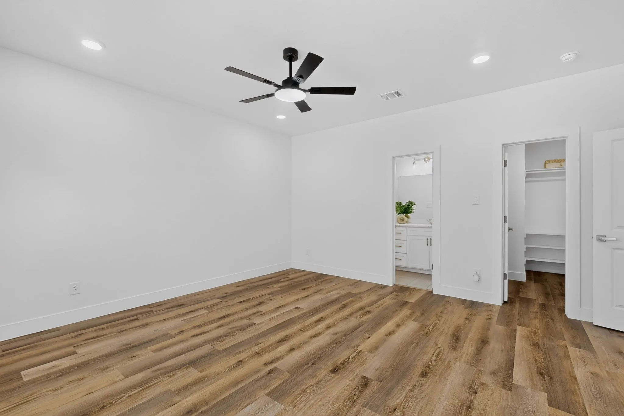 Spacious room featuring wood-finish flooring, recessed lighting, and a contemporary ceiling fan.