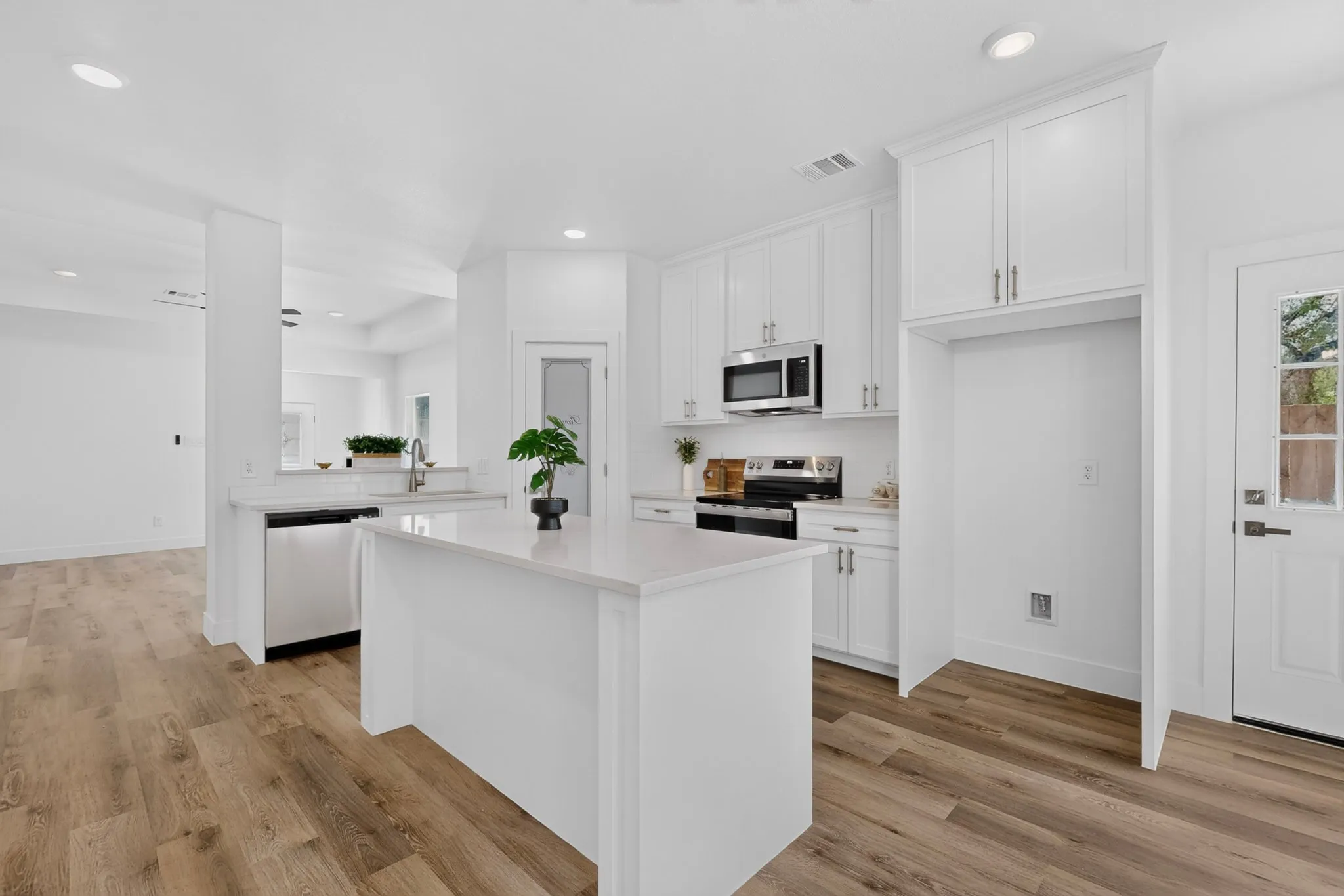 Kitchen featuring a center island, white cabinetry, stainless steel appliances, and wood-finish flooring