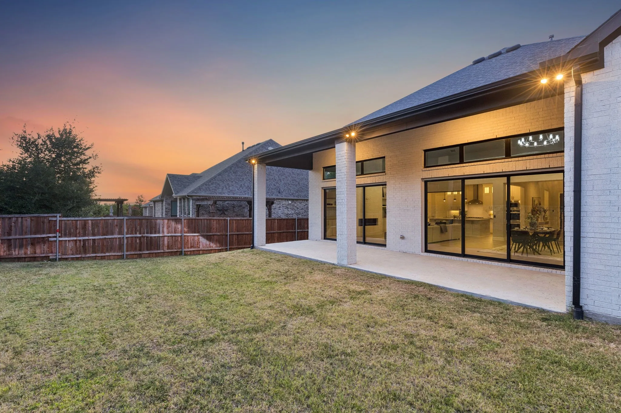As evening falls, the covered patio and pool-sized backyard become an inviting extension of the home.