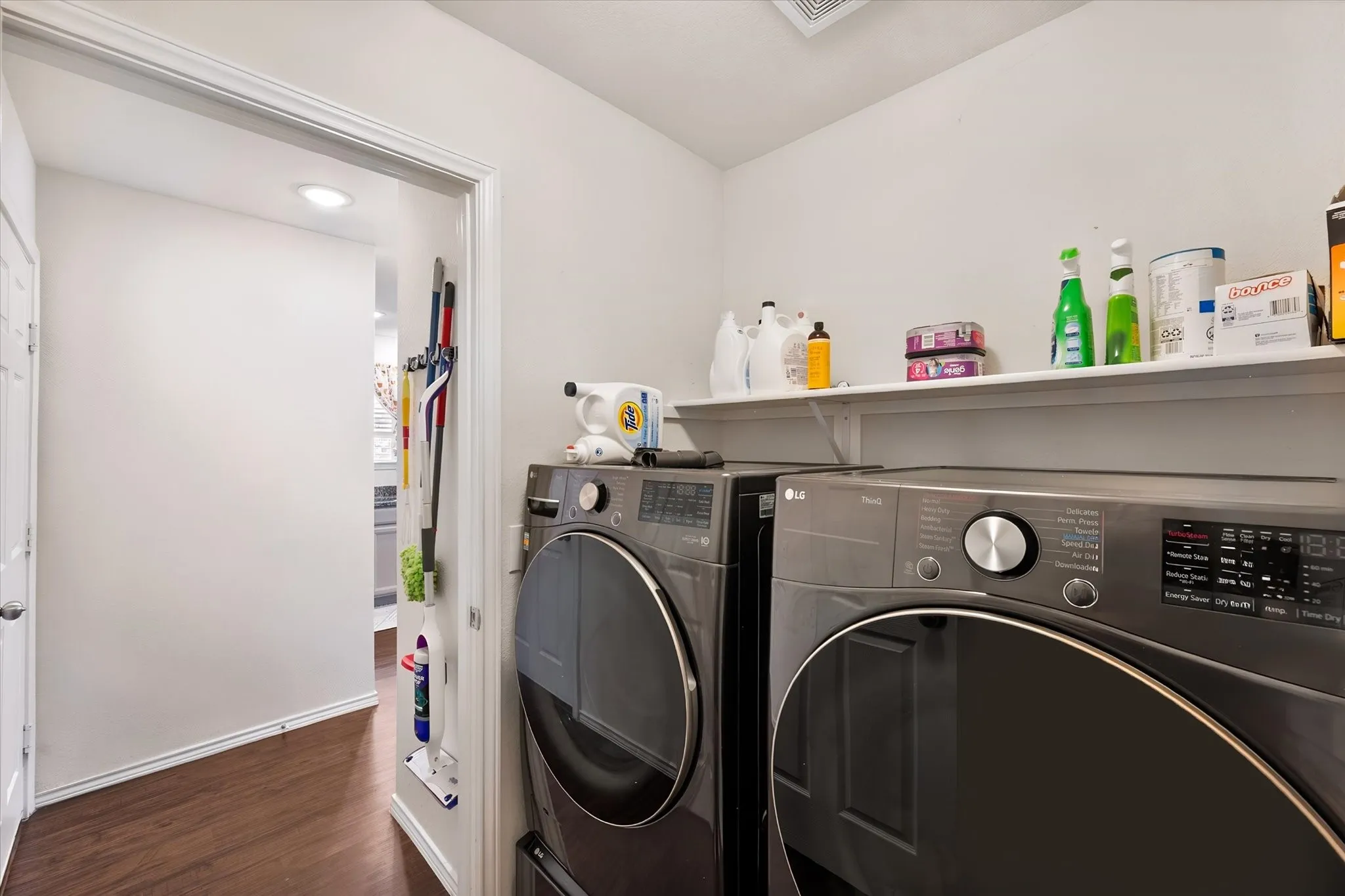 Laundry area featuring wood-finish flooring, recessed lighting, and wall-mounted shelving