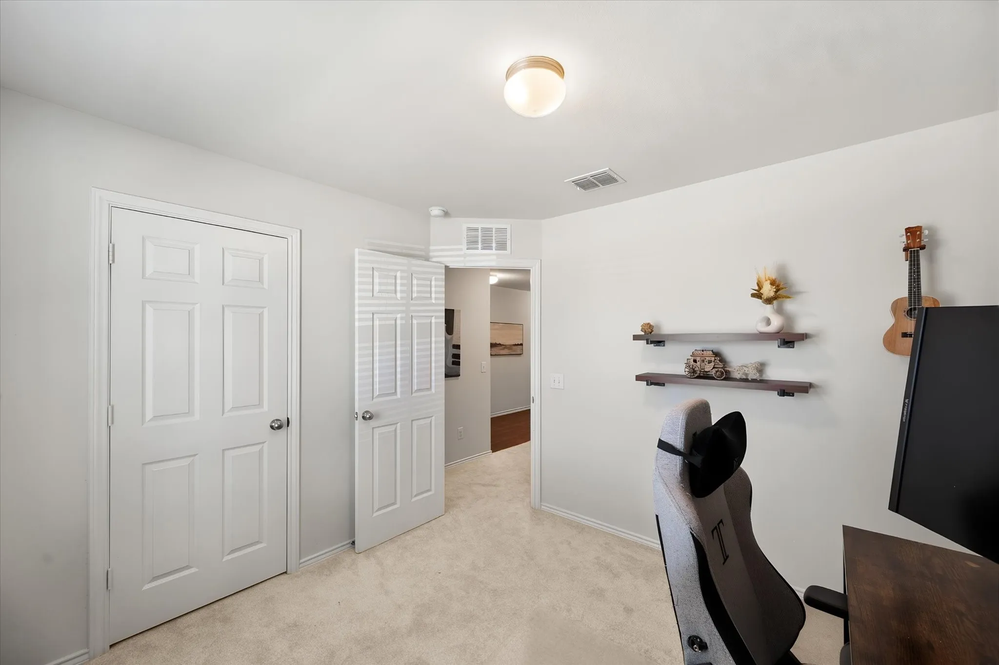 Versatile bonus room featuring neutral carpet flooring, multiple white six-panel closet doors, built-in wall shelving with dark finish, and recessed ceiling lighting