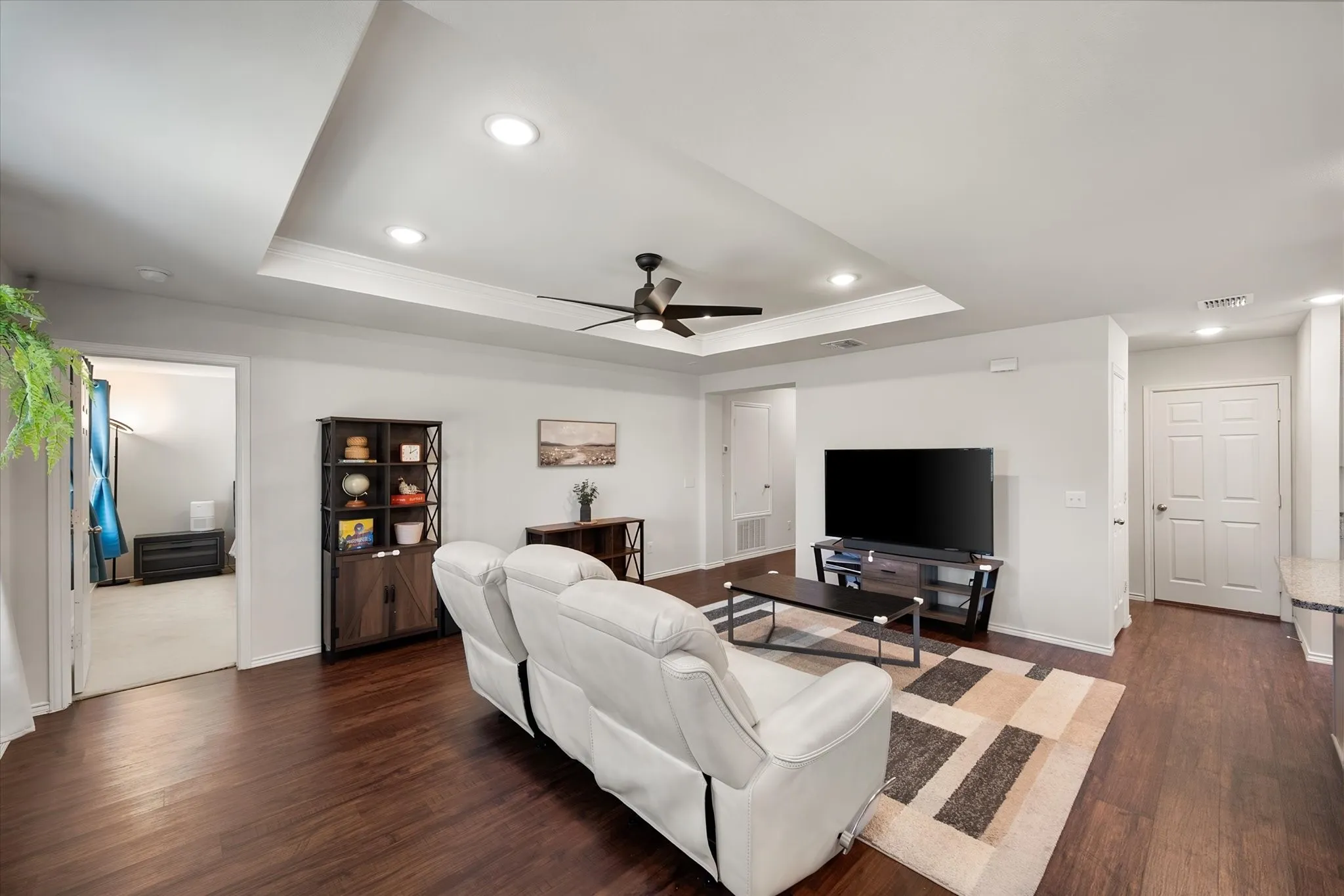 Tray ceiling with recessed lighting and a ceiling fan, wood-finish flooring, and white interior doors