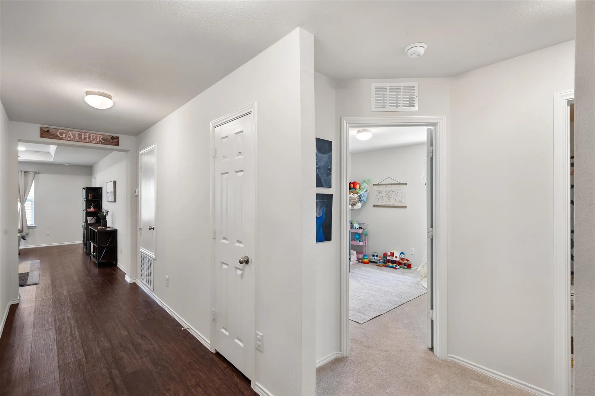 Hallway featuring wood-finish flooring, white paneled doors, and flush-mount lighting
