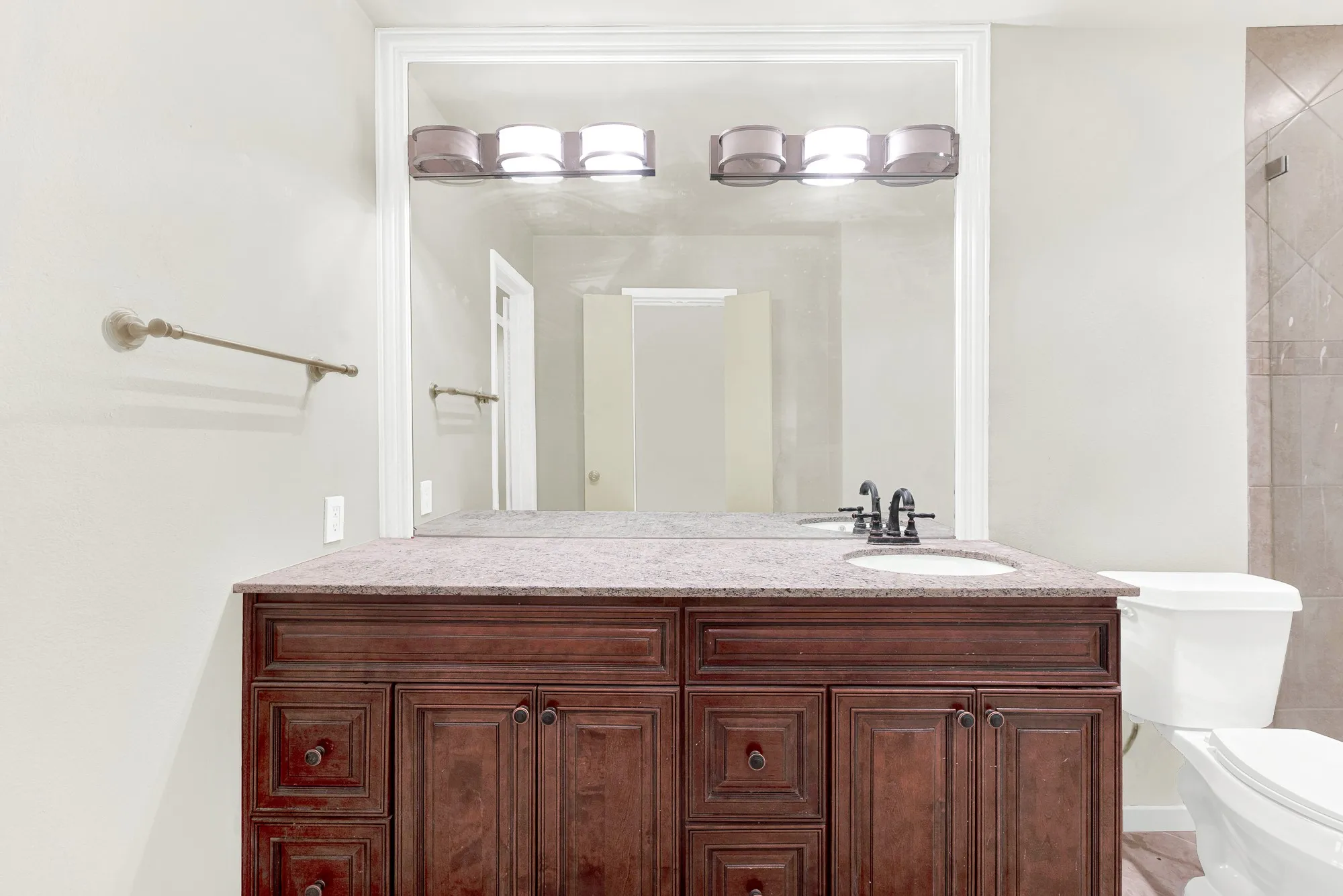 Vanity with wood-finish cabinetry, integrated sink, and dark-finish faucet