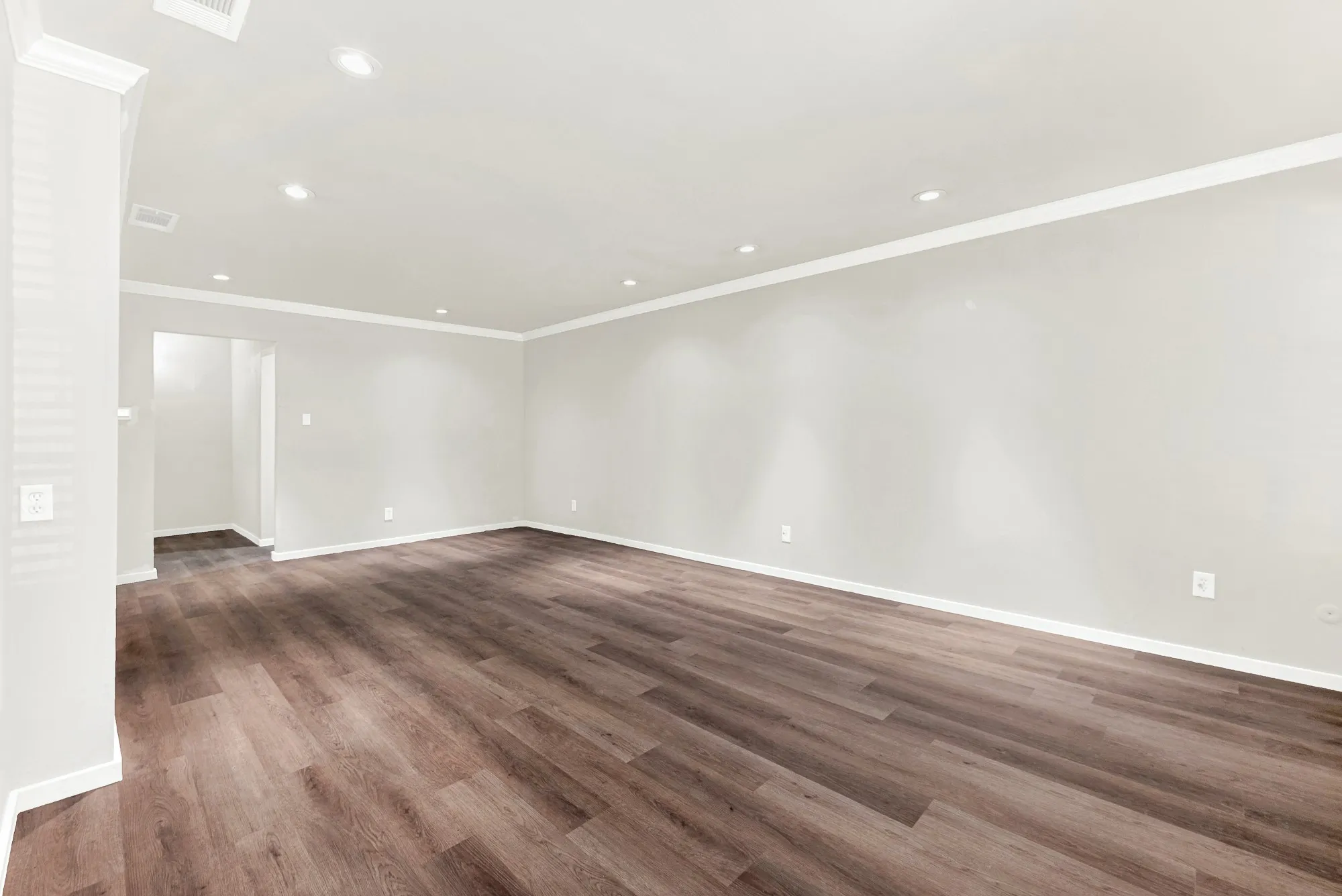 Spacious room with wood-finish flooring, recessed lighting, crown molding, and neutral wall tones